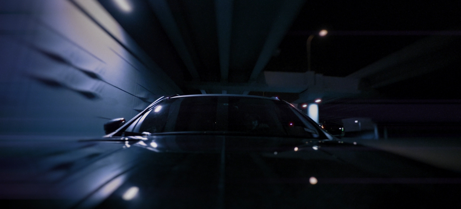 Hood-mounted car-mounted camera still of a vinyl-wrapped Maserati Levante under the I-35E Expressway tunnel at night in Dallas, Texas from a commercial advertisement for C2G Automotive with cinematography by Carpe Noctem Films, shot by Sam Casey