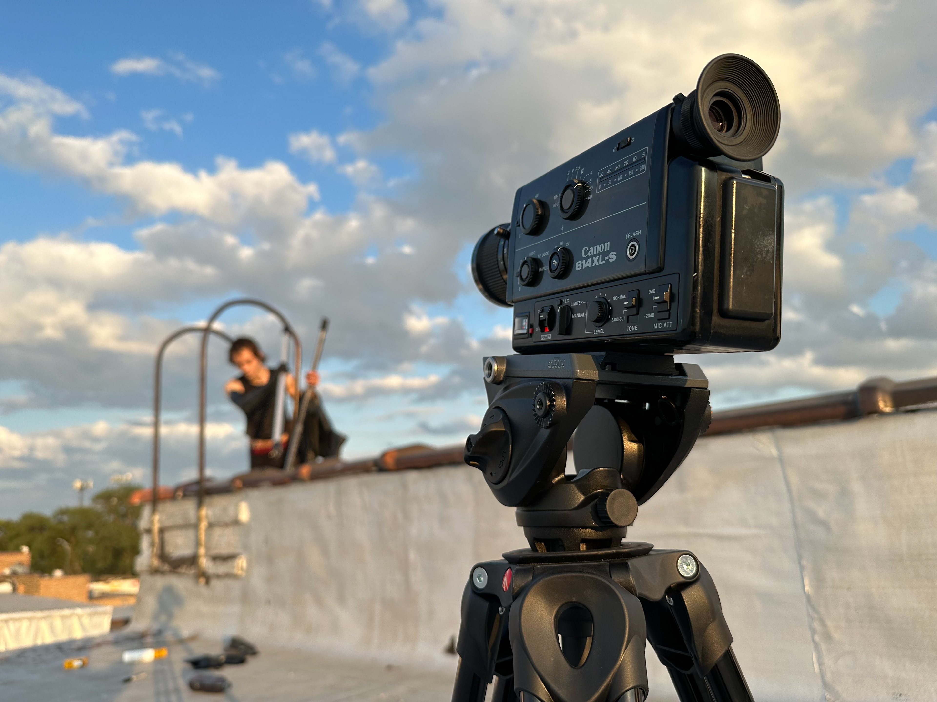 A Canon 814XL-S Super 8mm camera on a tripod with Ernest Kabashi in the background in 2023 on a rooftop an untitled upcoming project