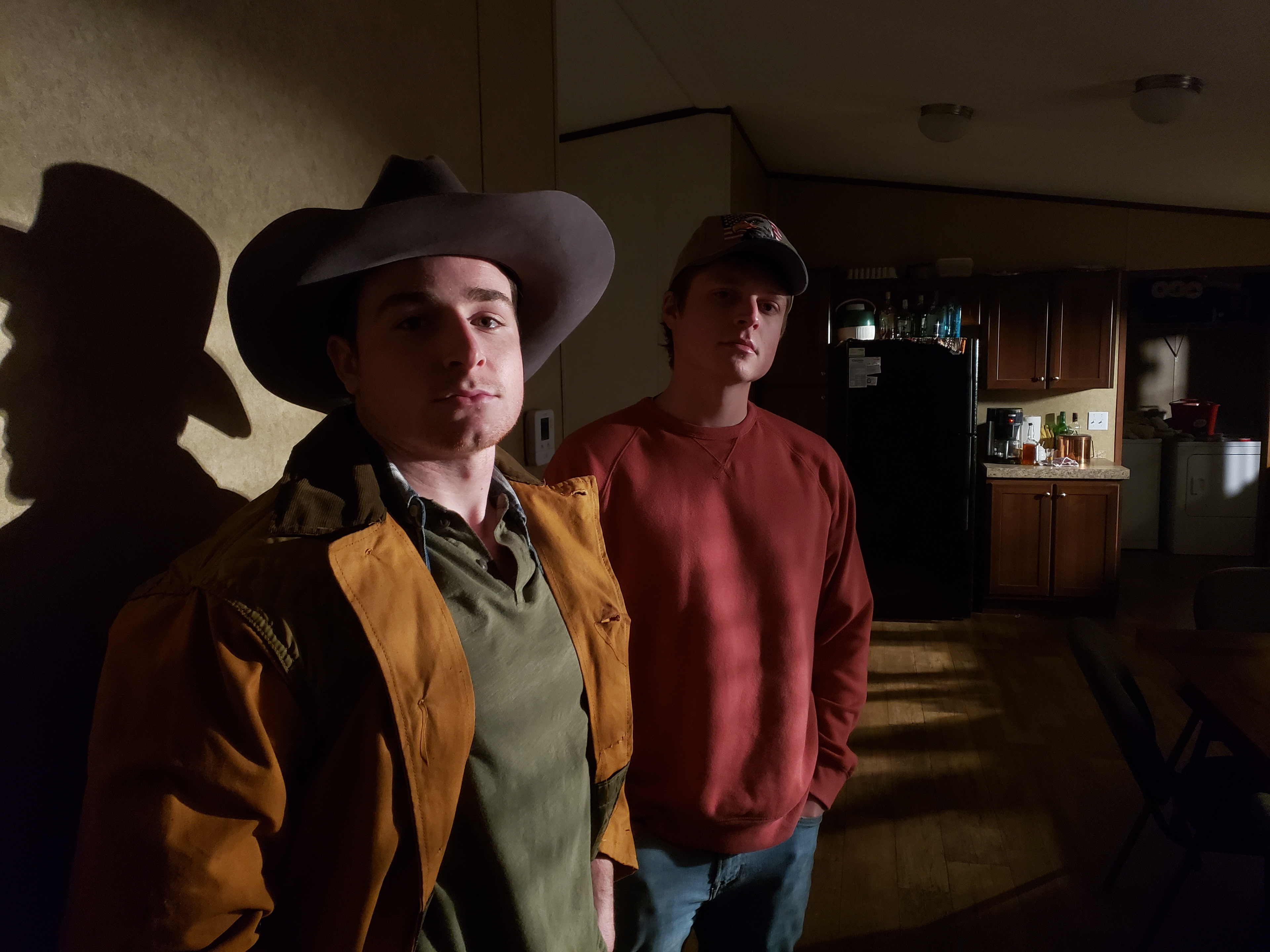 Garrett Avey and Buddy Love, photo by Sam Casey on the set of "Kingdom Come" in the kitchen of The Casey Ranch at night, with film lights illuminating them.