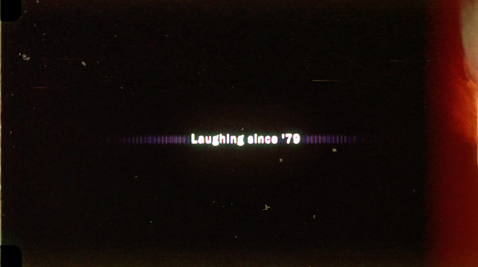 "Laughing since '79" animated CRT text still with lens reflections on a background with film burns in the "Laughing Since '79" commercial advertisement, preshow presentation, and parody of the AMC Theaters Nicole Kidman "We Make Movies Better" Advertisement for The Laugh Factory by Carpe Noctem Films