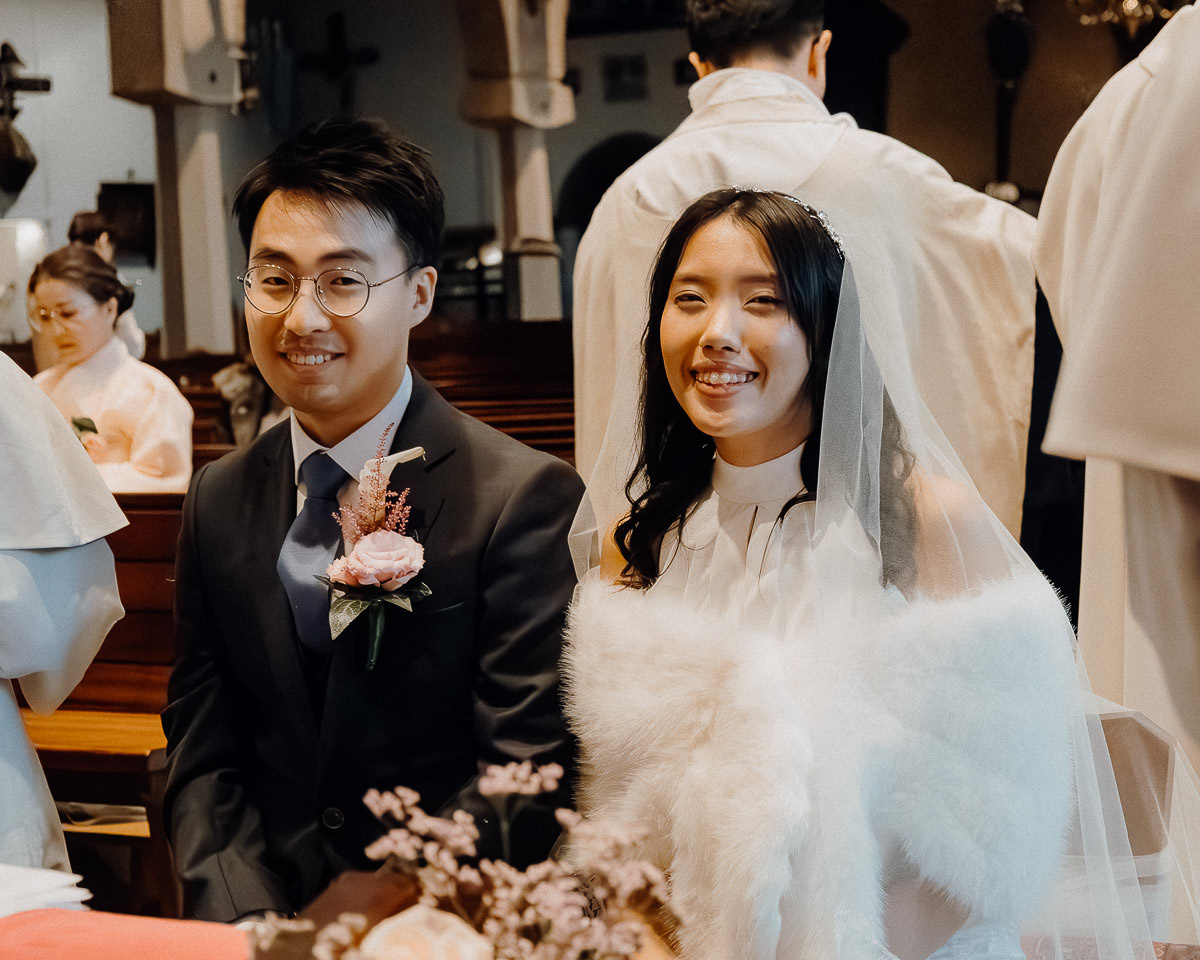 Newly weds smiling at the camera in their wedding.