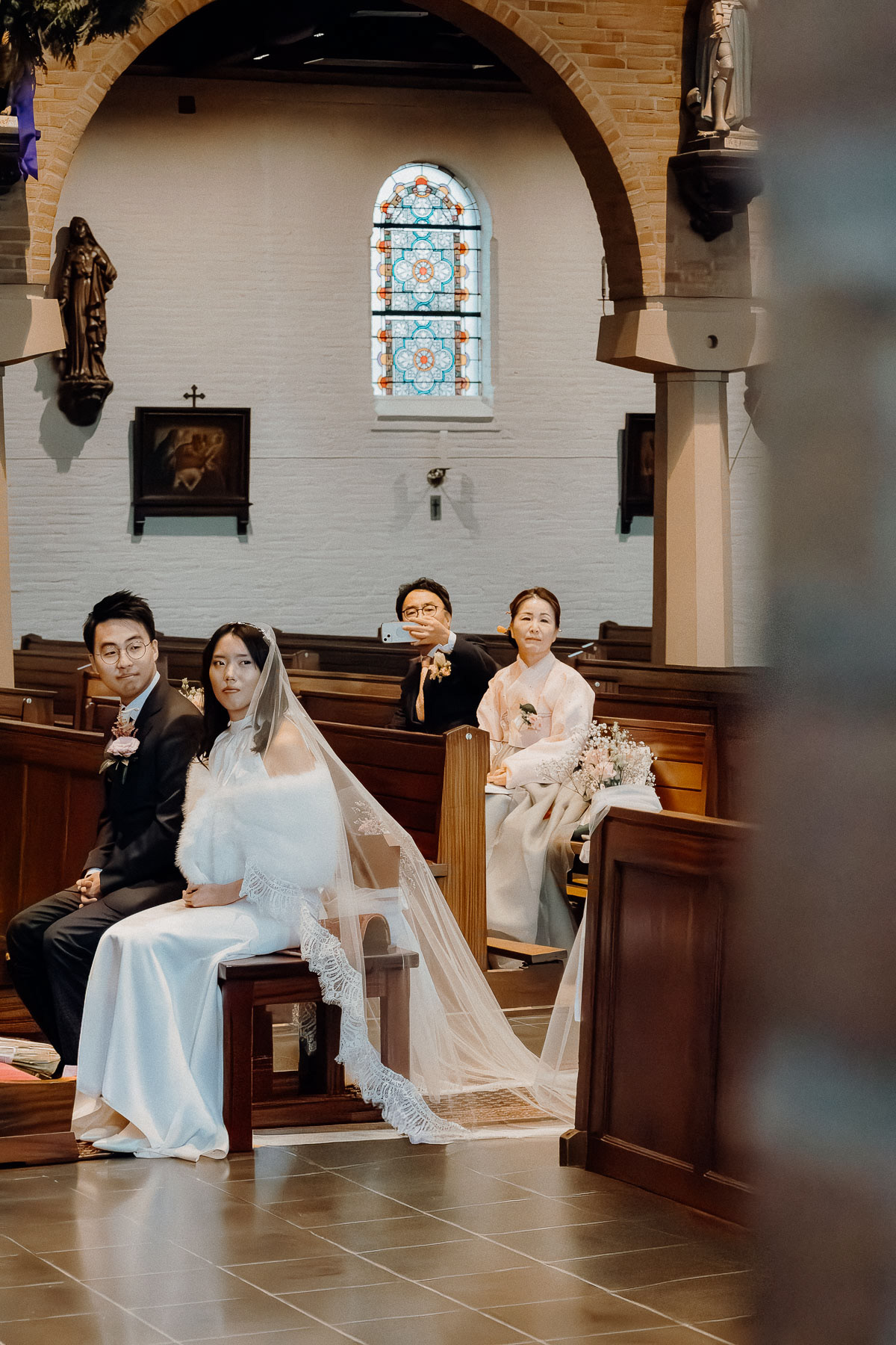 Bride, groom, and the groom's parents looking at the groom's brother.