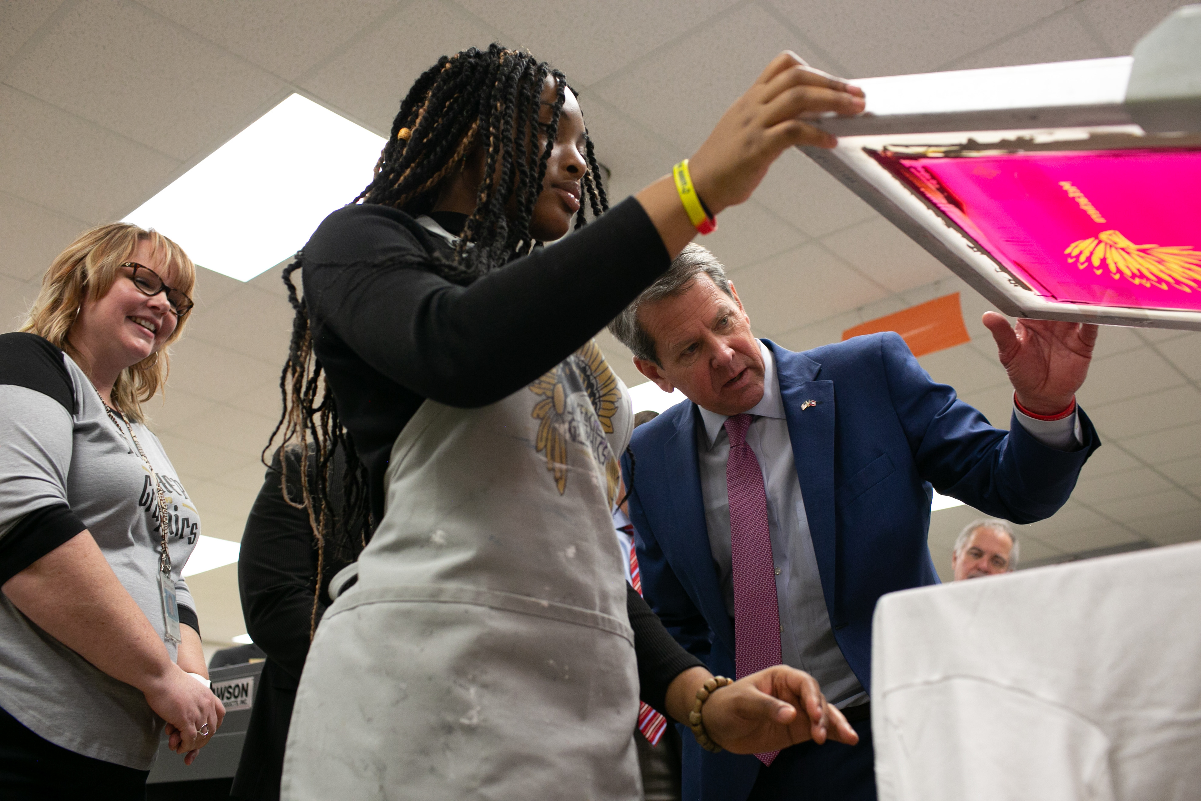 Gov. Brian Kemp of Georgia watches a student print a t-shirt using a screen printing press during a tour of McEachern High School in Powder Springs, Georgia, on Thursday, February 13, 2020.