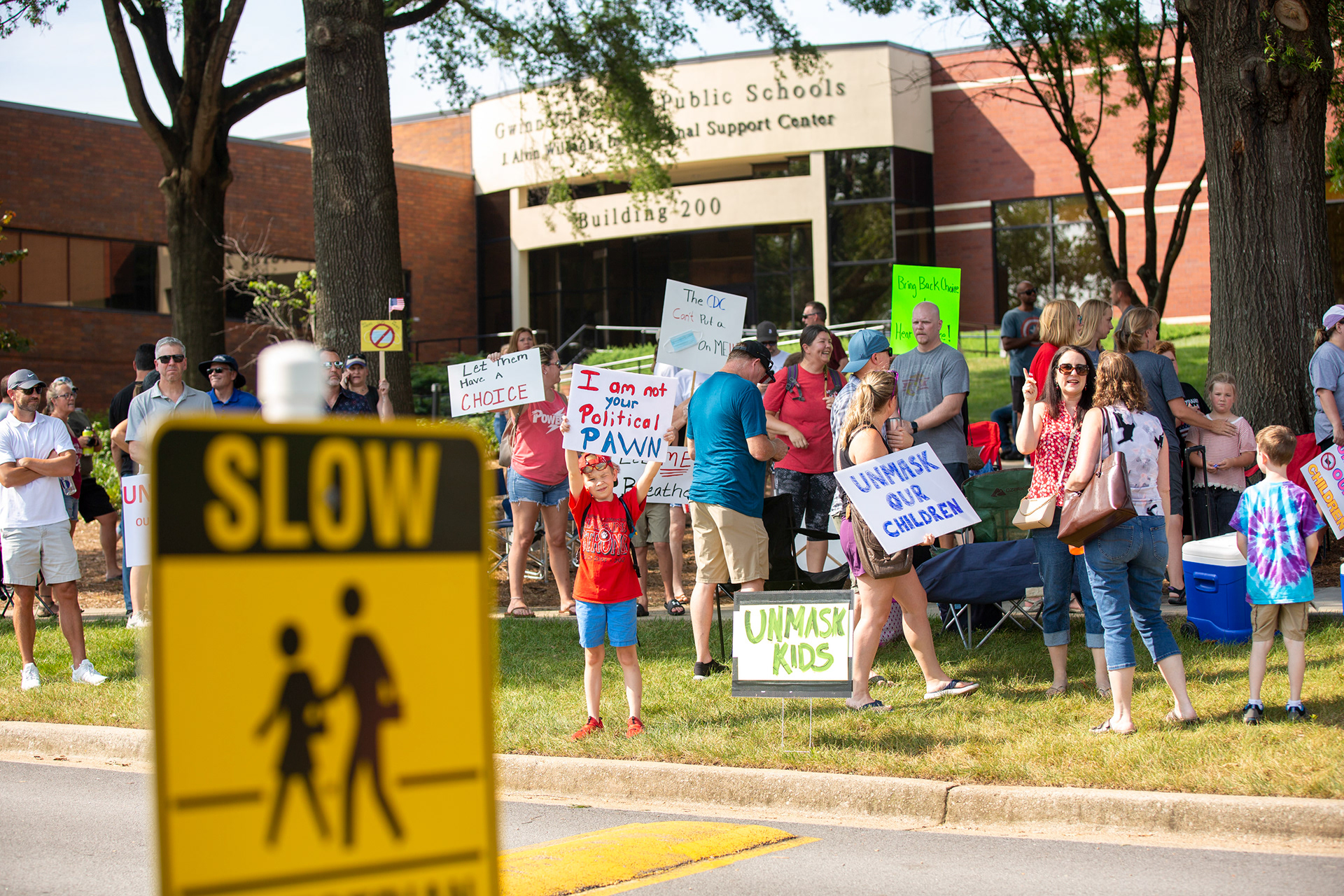 Gavin Renaud, 8, center, protests with other Gwinnett County residents outside the confirmation for new Gwinnett County Public Schools superintendent Calvin Watts at the J. Alvin Wilbanks Instructional Support Center in Suwanee, Georgia, on Friday, July 30, 2021.