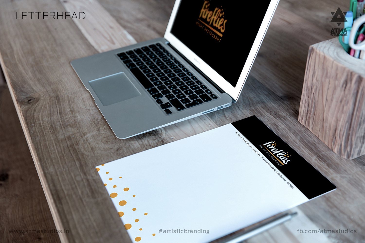 Fireflies letterhead mockup beside a laptop on a wooden desk