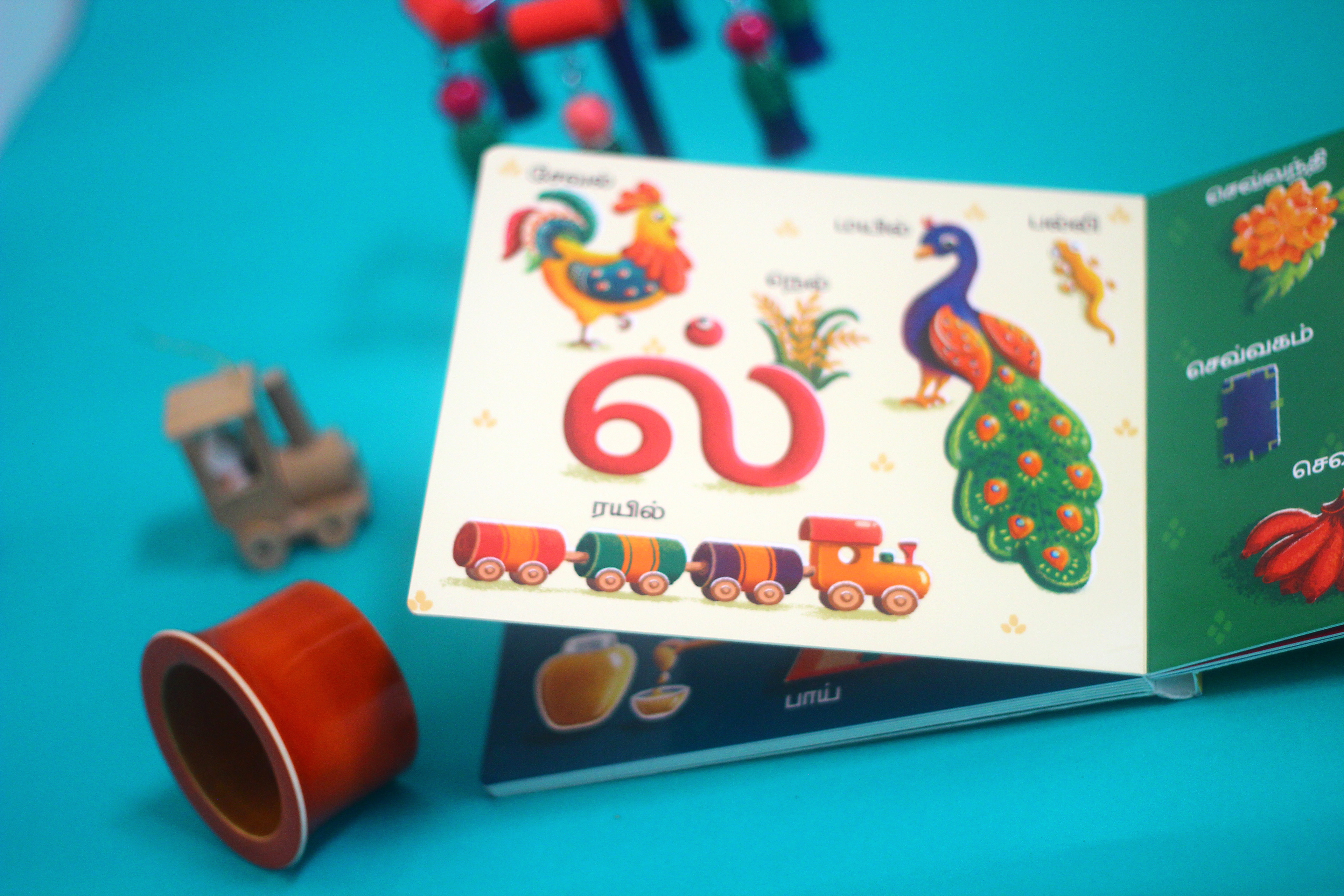 Vidhaippom Meithamizhai Tamil alphabet board book: page with a peacock for the letter la