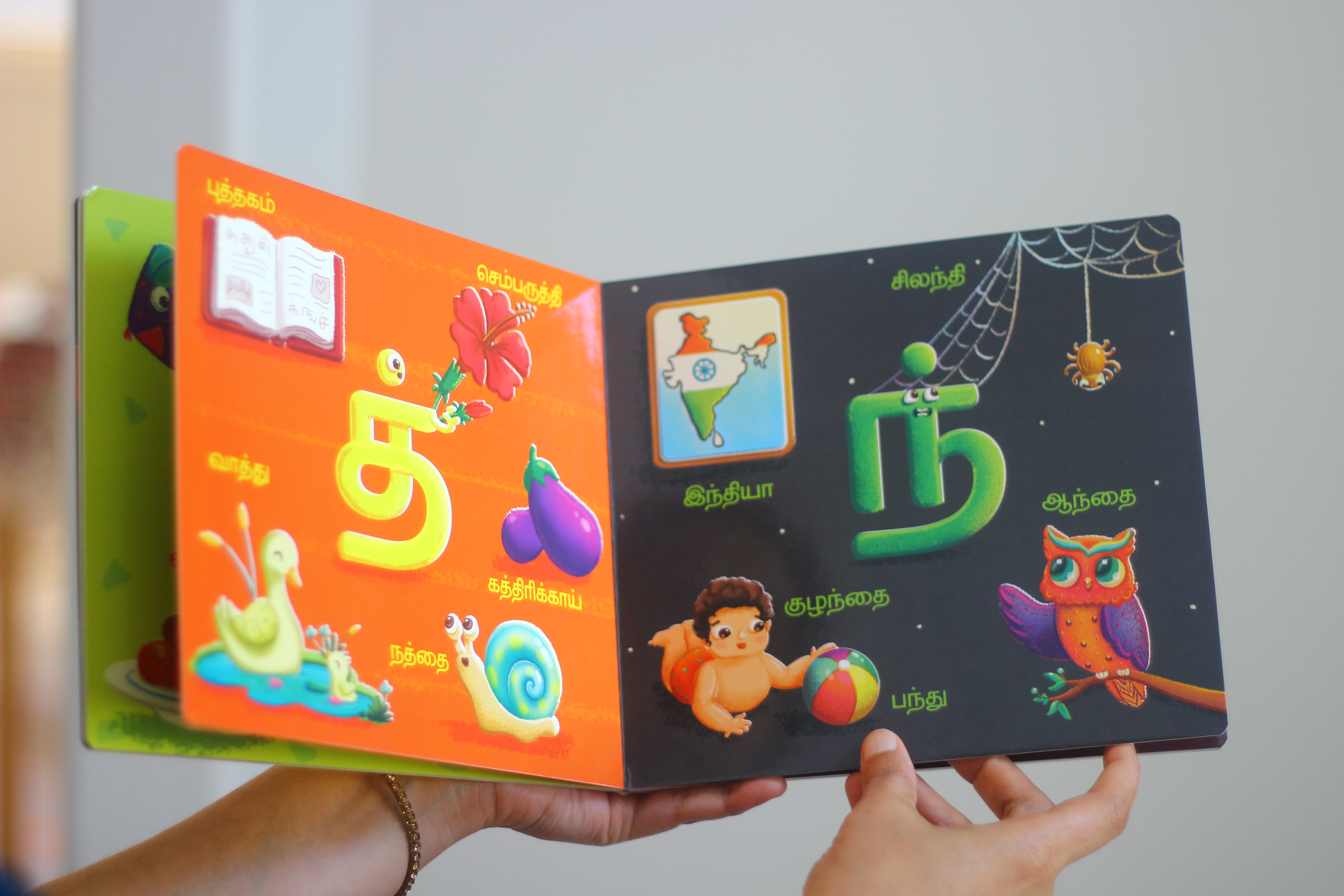 Vidhaippom Meithamizhai Tamil alphabet board book: open board book held in hands