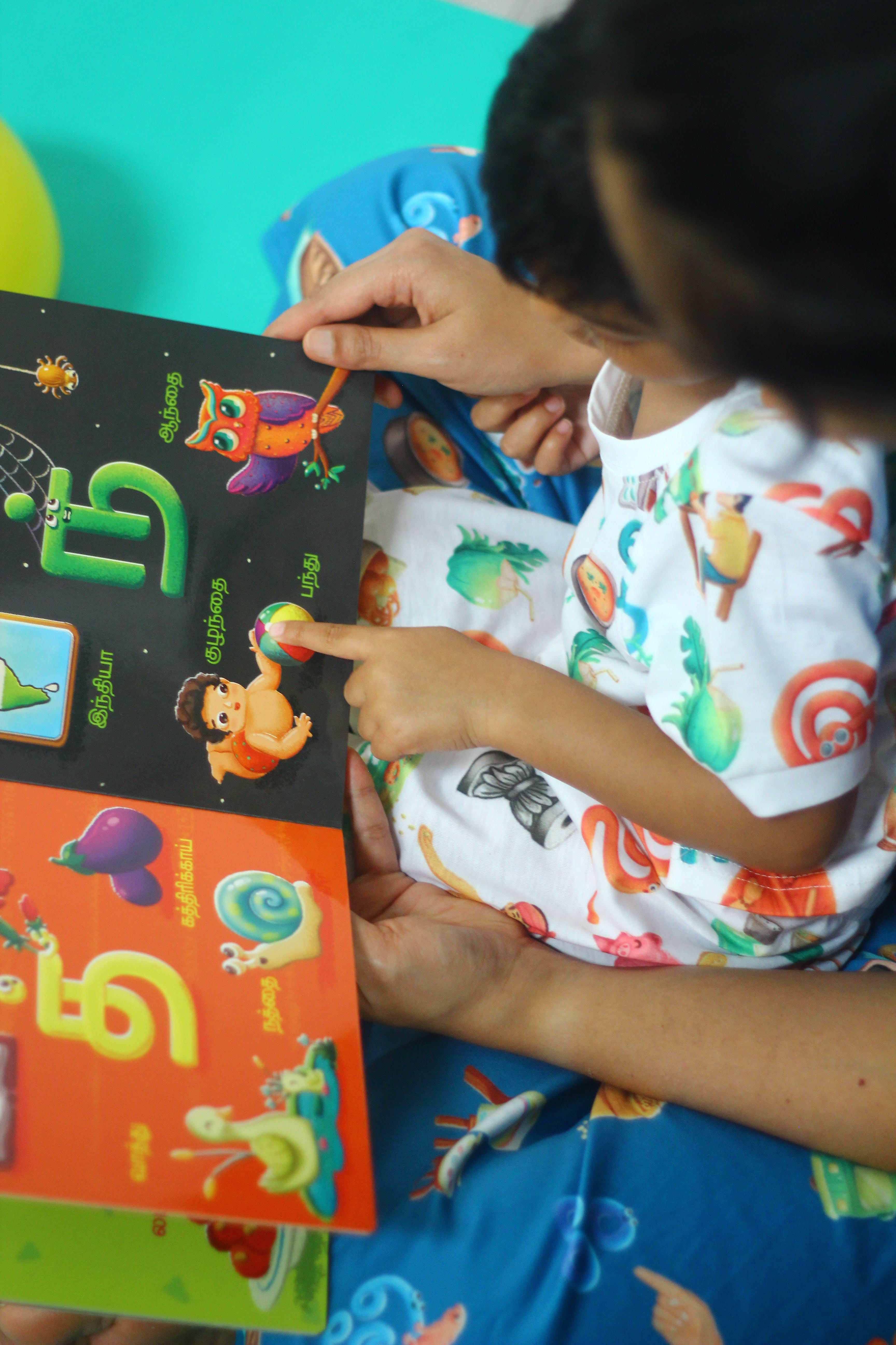 Vidhaippom Meithamizhai Tamil alphabet board book: child pointing at illustrated letters