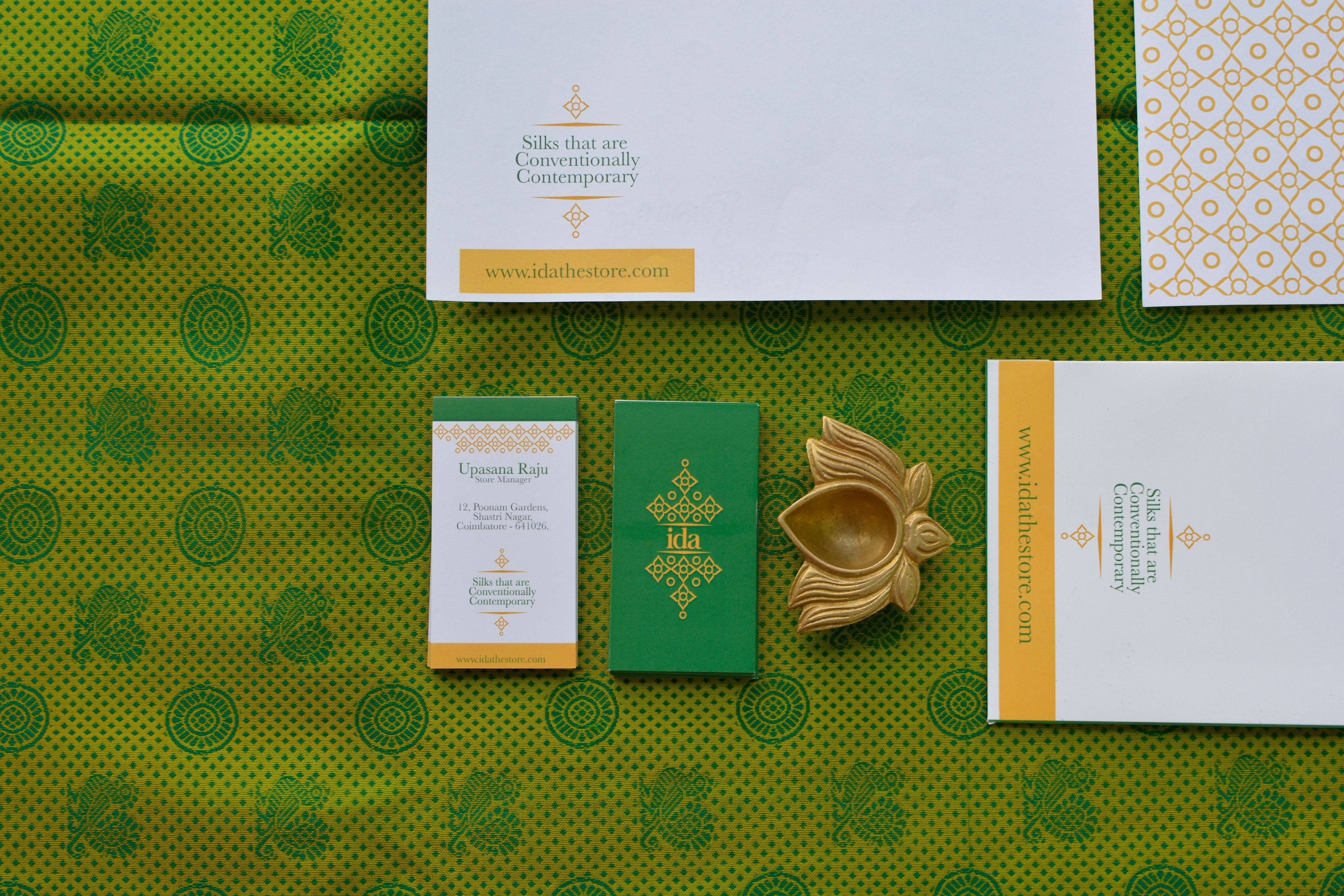 ida contemporary Kanchipuram silk sari brand: stationery set with letterhead, cards and a brass lamp on green silk