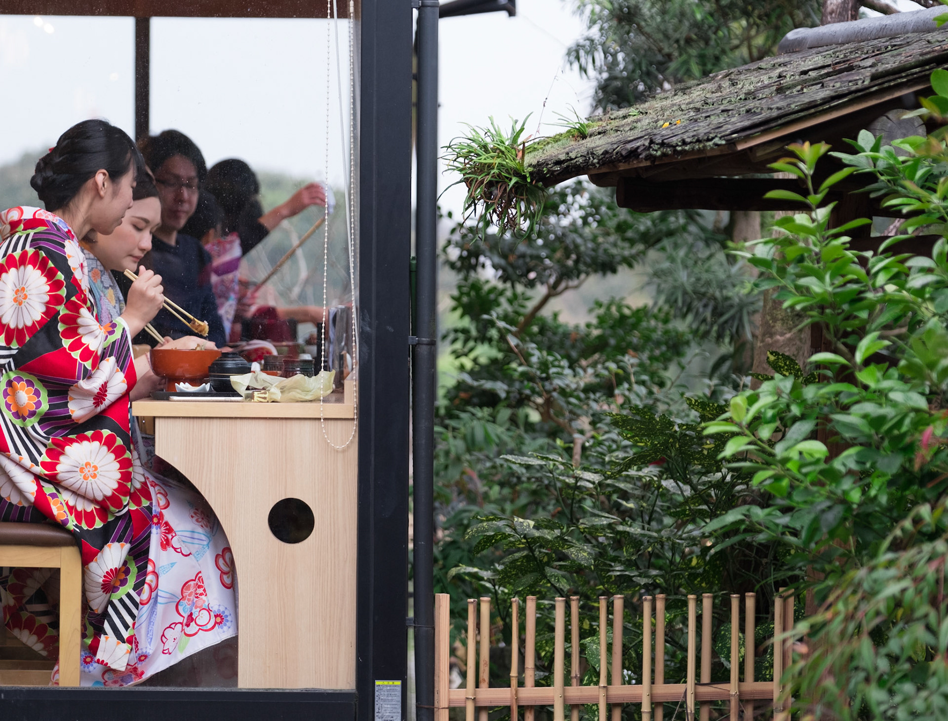 Freinds wearing kimonos eating lunch with chopsticks in the Ninenzaka and Sannenzaka area of Higashiyama, Kyoto.