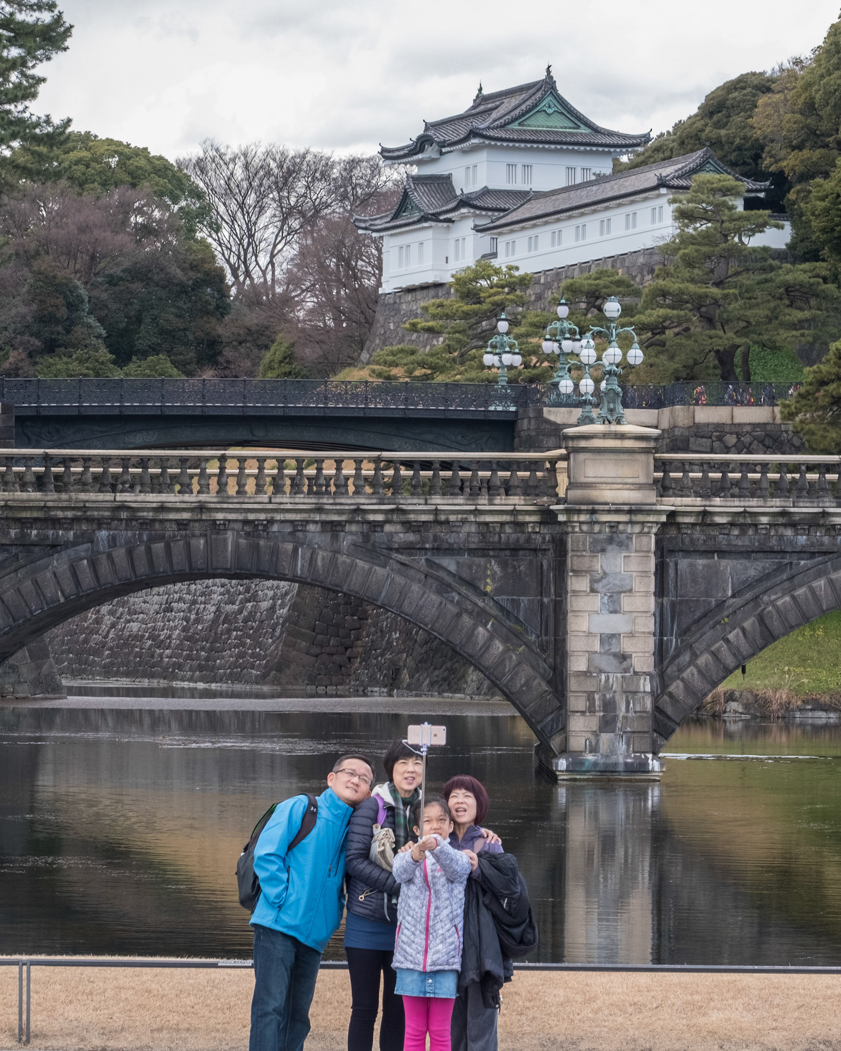 Family taking a selfie photo as they enjoy the Tokyo Imperial Castle and the Nijubashi bridge.
