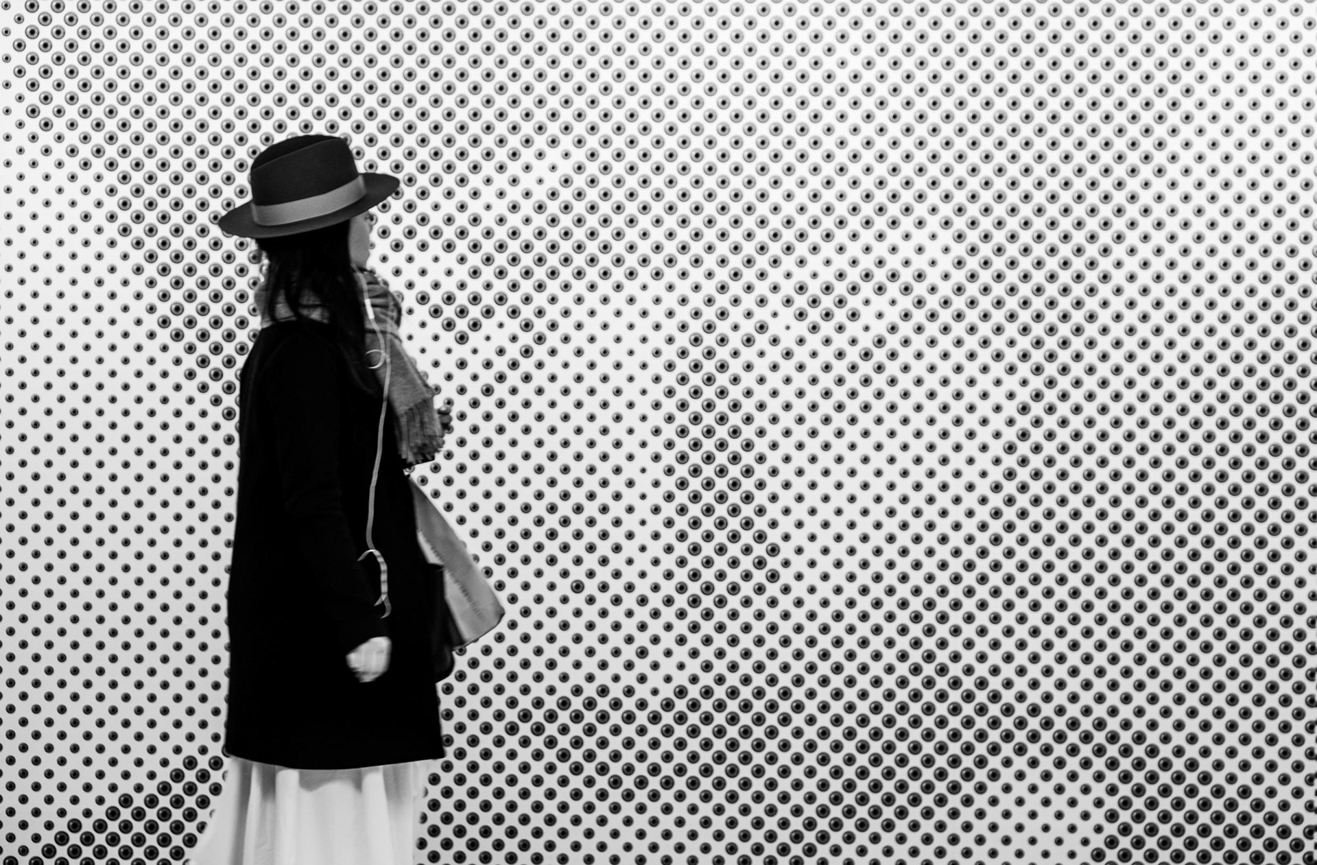 Wall art that is only visible when you back away from the wall. Woman trying to figure out what it is.