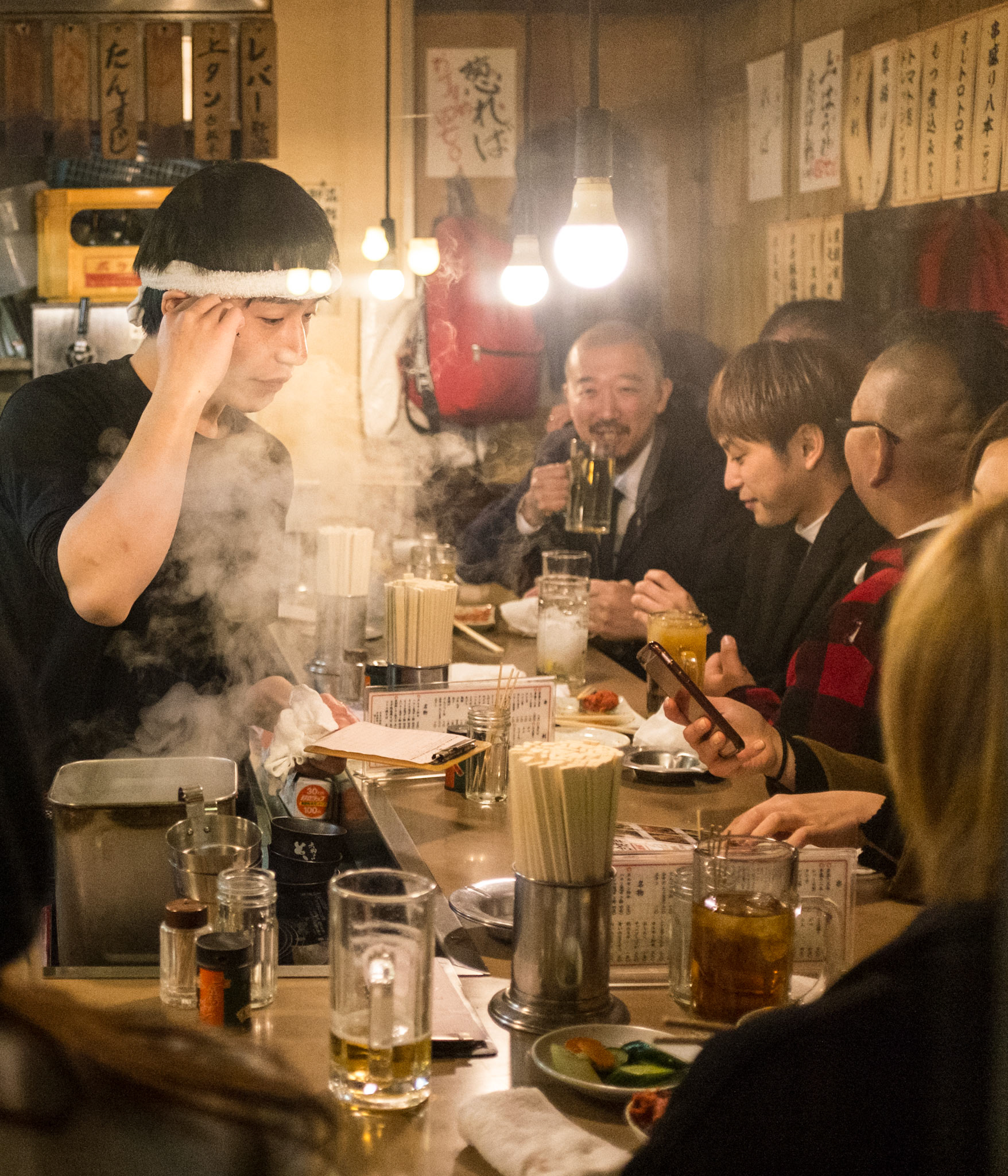 Friends enjoying beer at an Izakaya pub in Piss Alley, aka Omoide Yokocho or Shomben Yokocho
