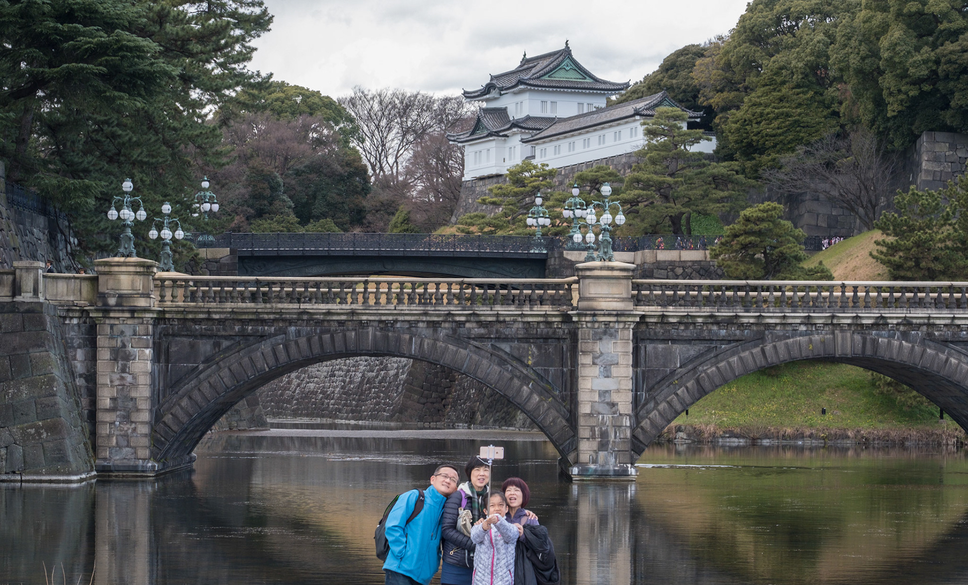 Family taking a selfie photo as they enjoy the Tokyo Imperial Castle and the Nijubashi bridge.