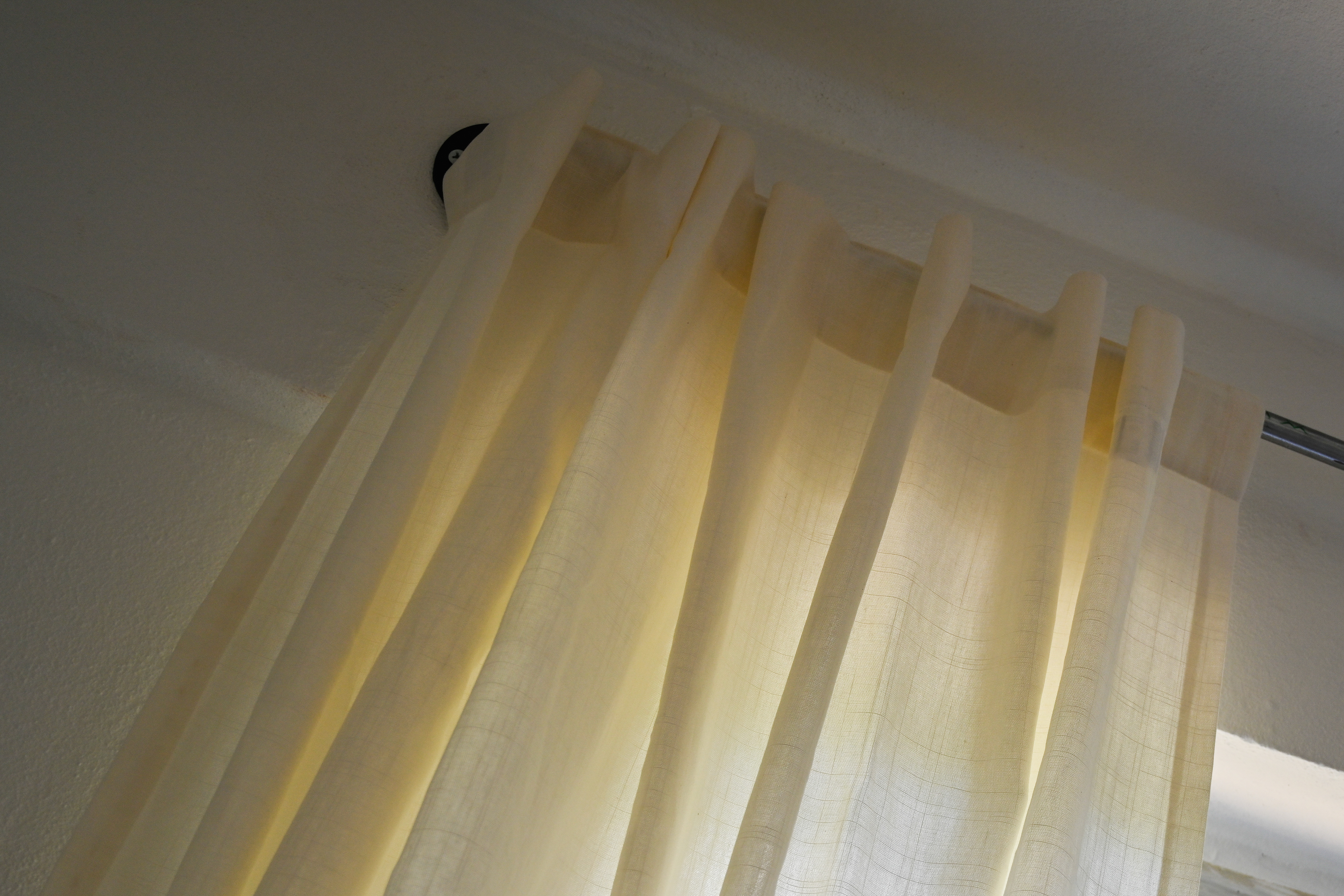 Natural white and beige curtains gently filtering warm sunlight in the master suite at Hacienda Eterna Primavera, creating a soft, cozy atmosphere.