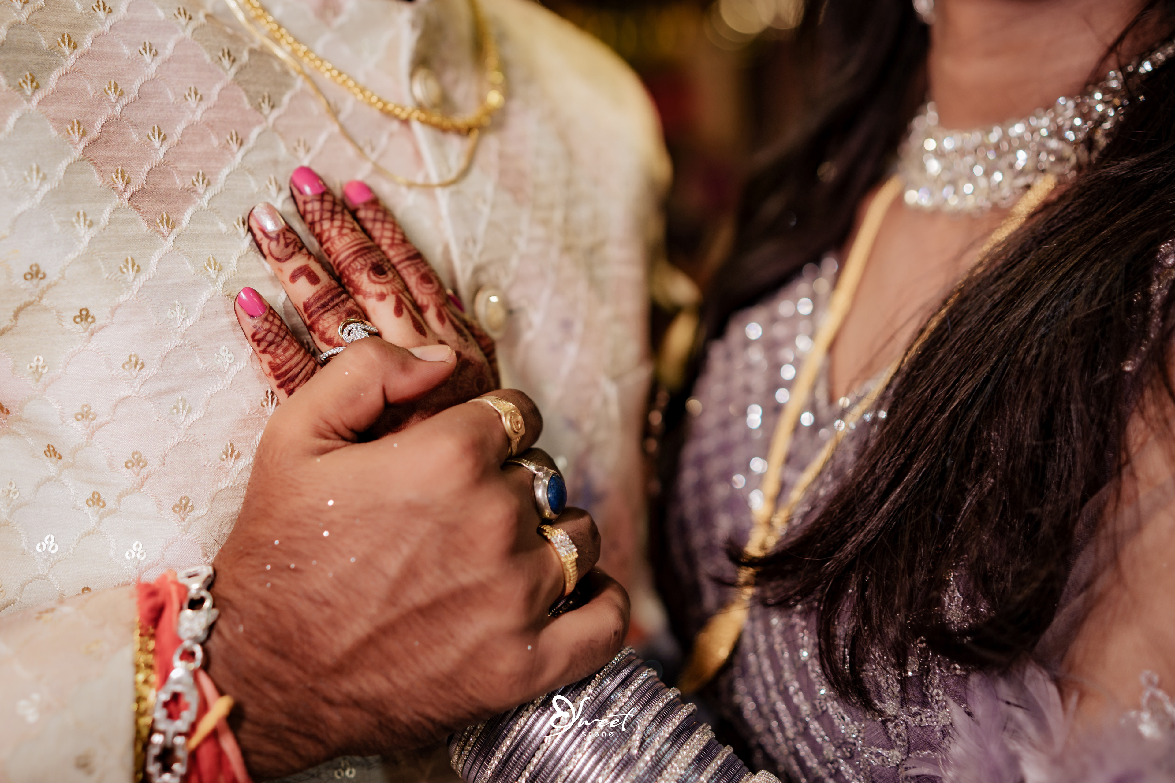 Prakhar and Madhu walking hand in hand as they enter the hall, the chandeliers above them casting a warm glow on their smiling faces
