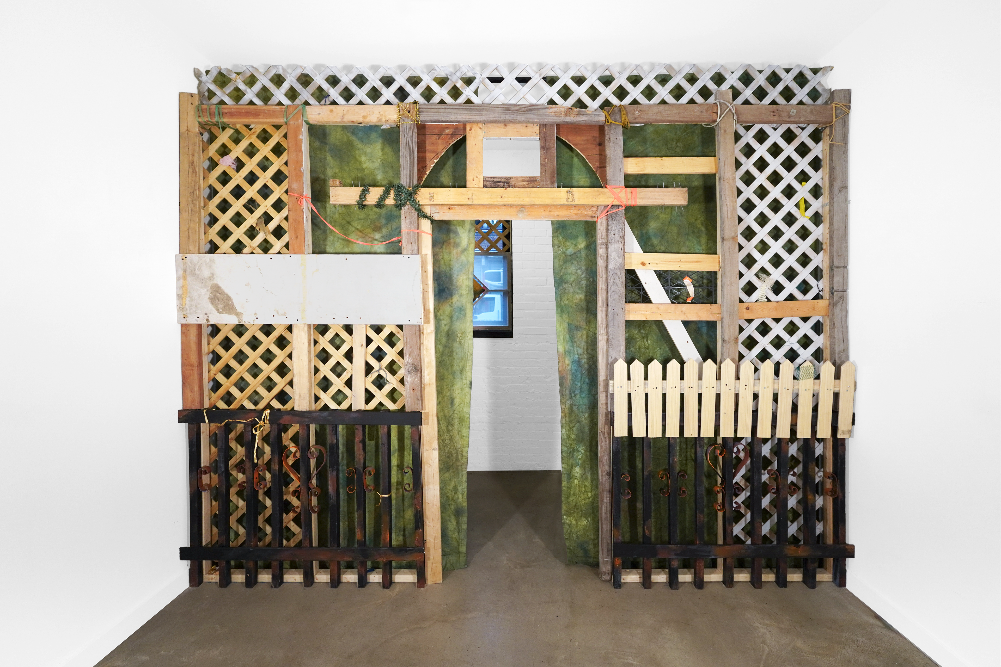 Meinzer and Victoria Reshetnikov Hush Lobby, 2026  Wood cutoffs from 37th Avenue, Grand Street, and 48th Street. Lattice from Facebook Marketplace. Slats from 3 bedframes. Deconstructed washing machine foundation from Middle Village. Shipping palettes from Connecticut and a new Sunnyside grocery store. 3D printed custom parts. Cords, produce netting, shoelaces, surveyor’s tape, plastic bags, braided strings. Pine. (Reshetnikov)  Canvas, tulle, fabric dye, colored pencil. (Meinzer)  4 ⅛’ X 11 ½’ (The approximate size of an average New York City balcony). (Wall Form) 2 ⅞’ x 4 ⅜’ (A quarter inch shorter in width and height of the gallery’s windows). (Window Forms)