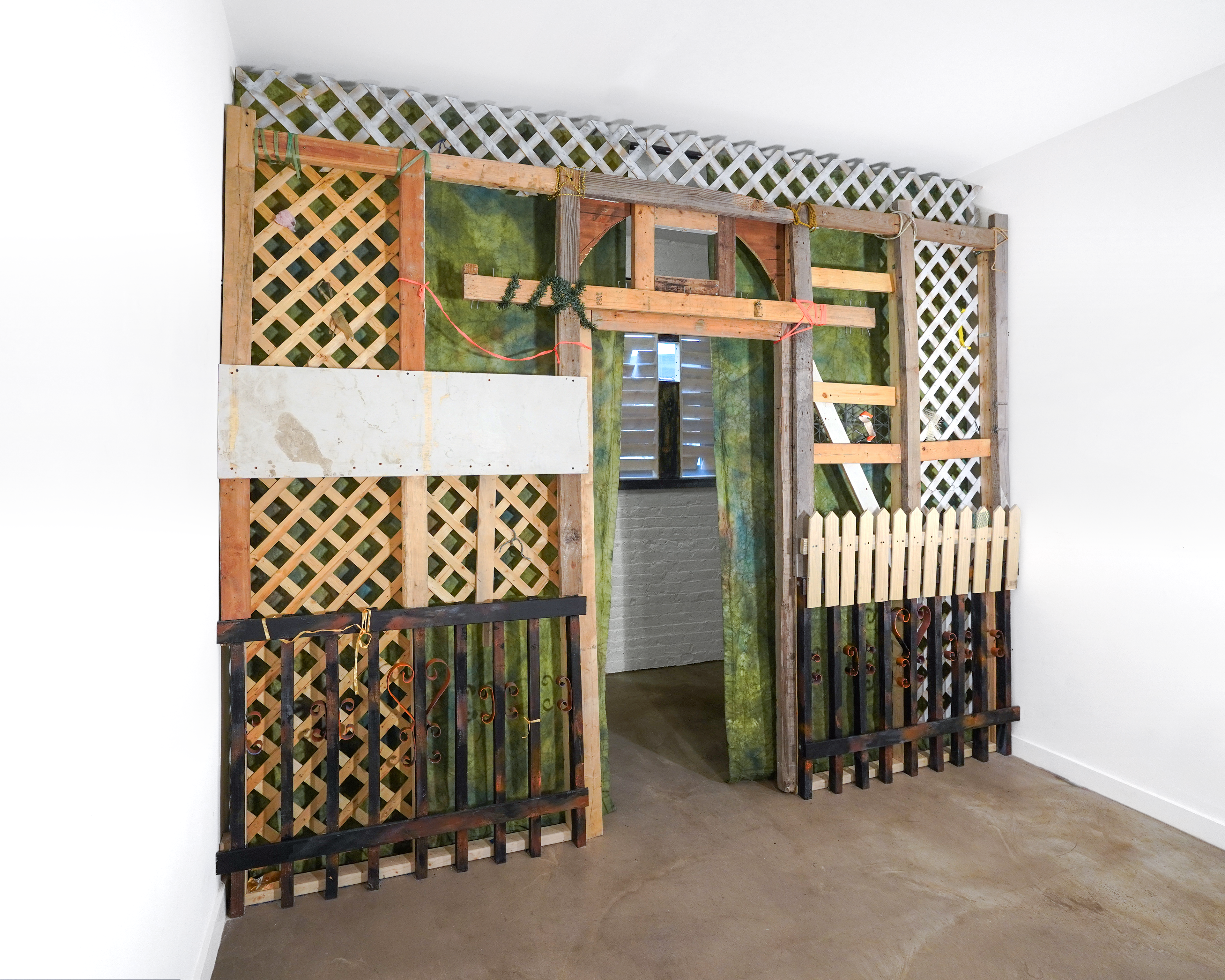 Meinzer and Victoria Reshetnikov Hush Lobby, 2026  Wood cutoffs from 37th Avenue, Grand Street, and 48th Street. Lattice from Facebook Marketplace. Slats from 3 bedframes. Deconstructed washing machine foundation from Middle Village. Shipping palettes from Connecticut and a new Sunnyside grocery store. 3D printed custom parts. Cords, produce netting, shoelaces, surveyor’s tape, plastic bags, braided strings. Pine. (Reshetnikov)  Canvas, tulle, fabric dye, colored pencil. (Meinzer)  4 ⅛’ X 11 ½’ (The approximate size of an average New York City balcony). (Wall Form) 2 ⅞’ x 4 ⅜’ (A quarter inch shorter in width and height of the gallery’s windows). (Window Forms)