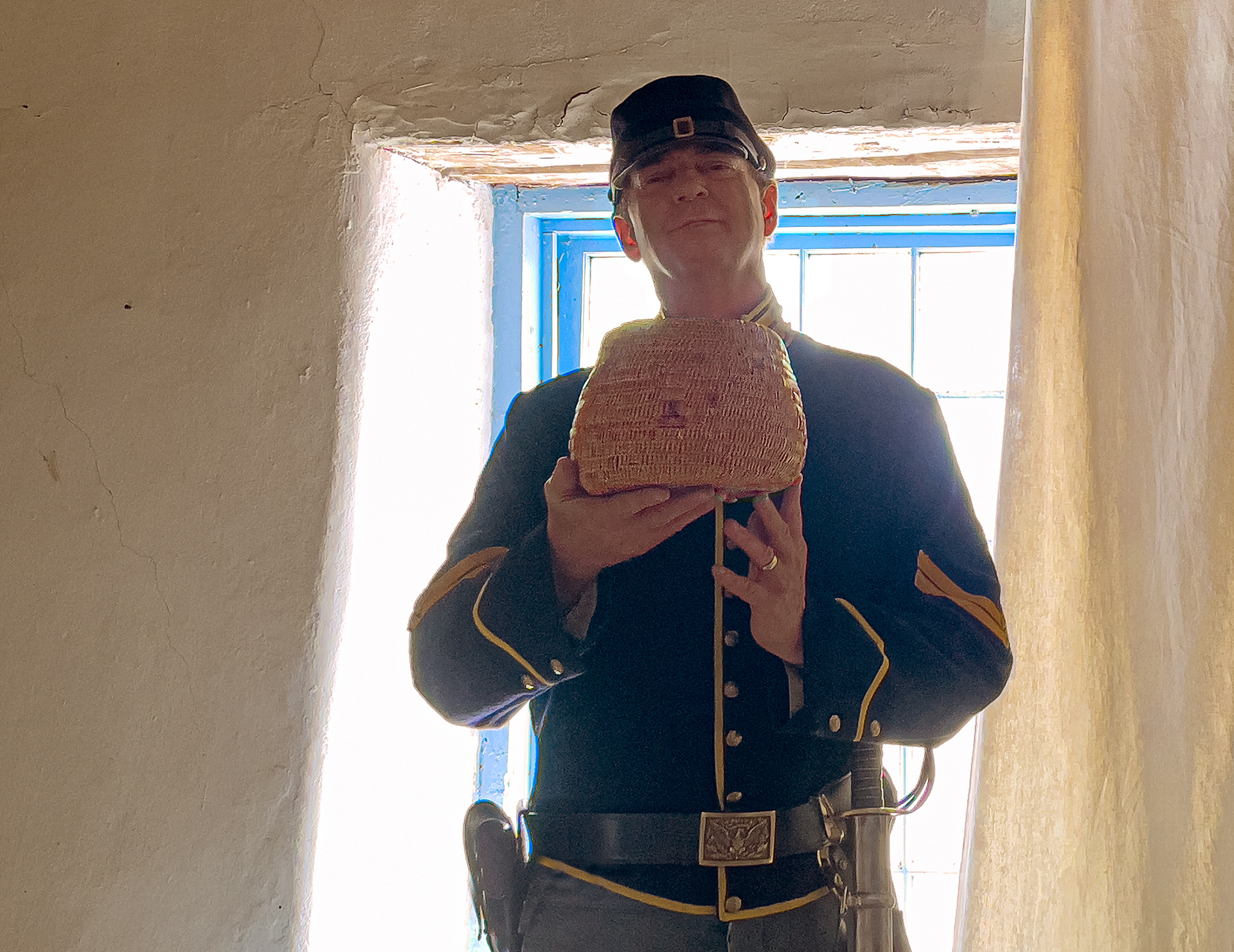 Showing a 19th century Jicarilla Apache basket while in cavalry uniform