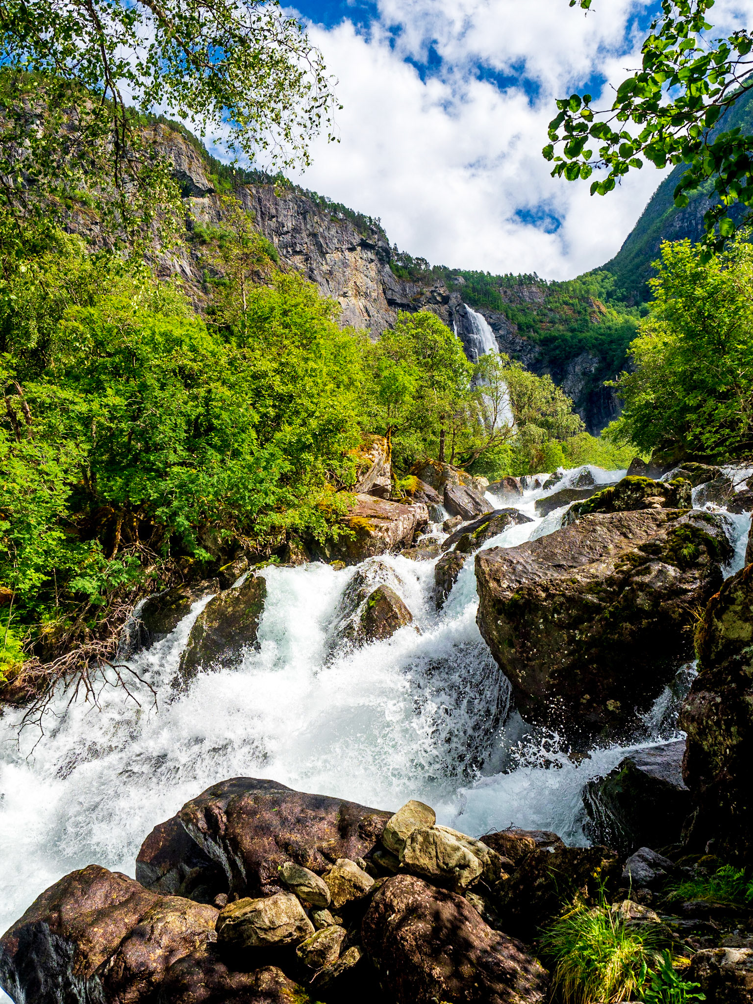 Der Aufstieg zum Feigefossen ist ein schöner Spaziergang und geht fast die ganze Zeit an seinem reißenden Strom entlang. Hier im Hintergrund sieht man den Wasserfall schon.

The ascend to Feigefossen is a nice walk and goes along it´s rough stream for most of the time. You can see the waterfall in the background