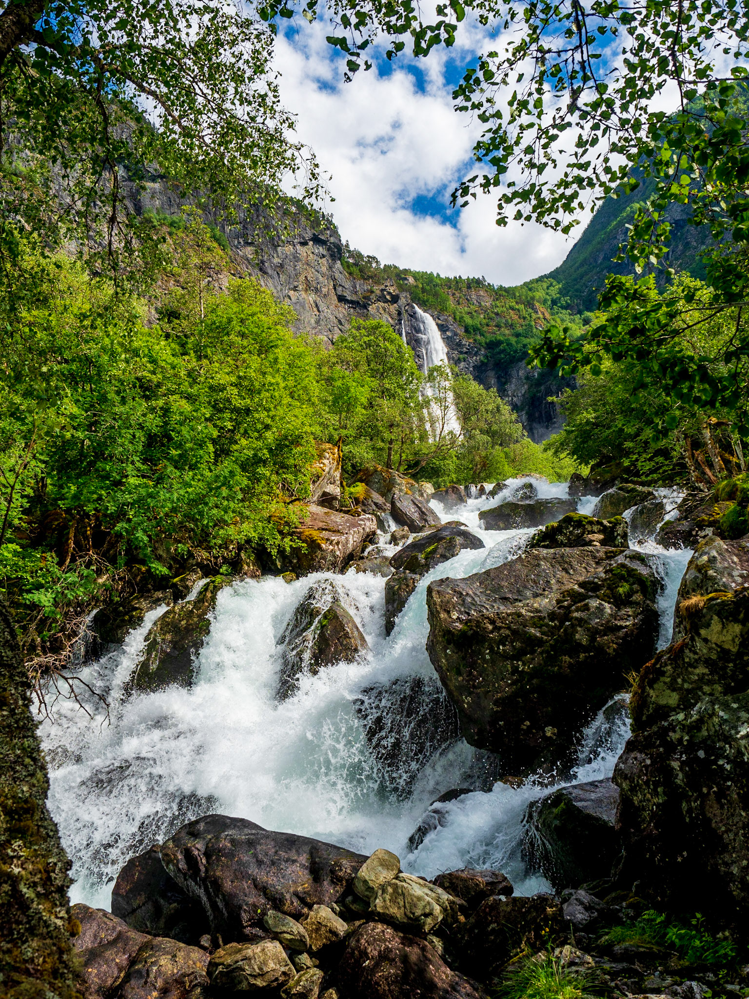Der Aufstieg zum Feigefossen ist ein schöner Spaziergang und geht fast die ganze Zeit an seinem reißenden Strom entlang. Hier im Hintergrund sieht man den Wasserfall schon.

The ascend to Feigefossen is a nice walk and goes along it´s rough stream for most of the time. You can see the waterfall in the background