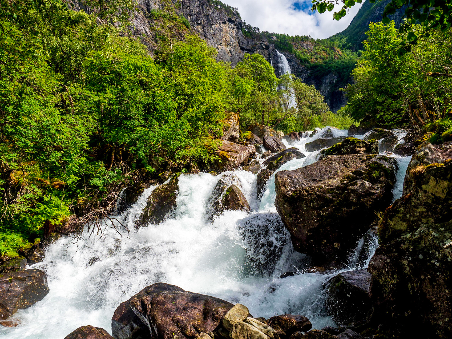 Der Aufstieg zum Feigefossen ist ein schöner Spaziergang und geht fast die ganze Zeit an seinem reißenden Strom entlang. Hier im Hintergrund sieht man den Wasserfall schon.

The ascend to Feigefossen is a nice walk and goes along it´s rough stream for most of the time. You can see the waterfall in the background