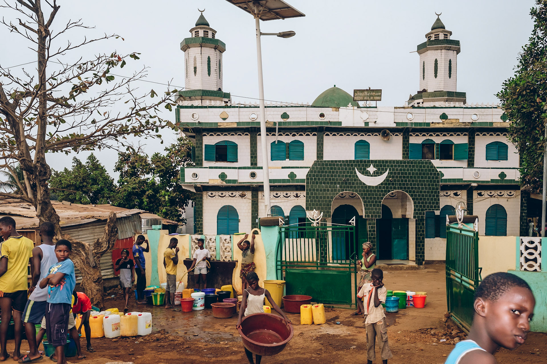 People fetch water from a well in front of a mosque in Nongo. Conakry, Guinea.
