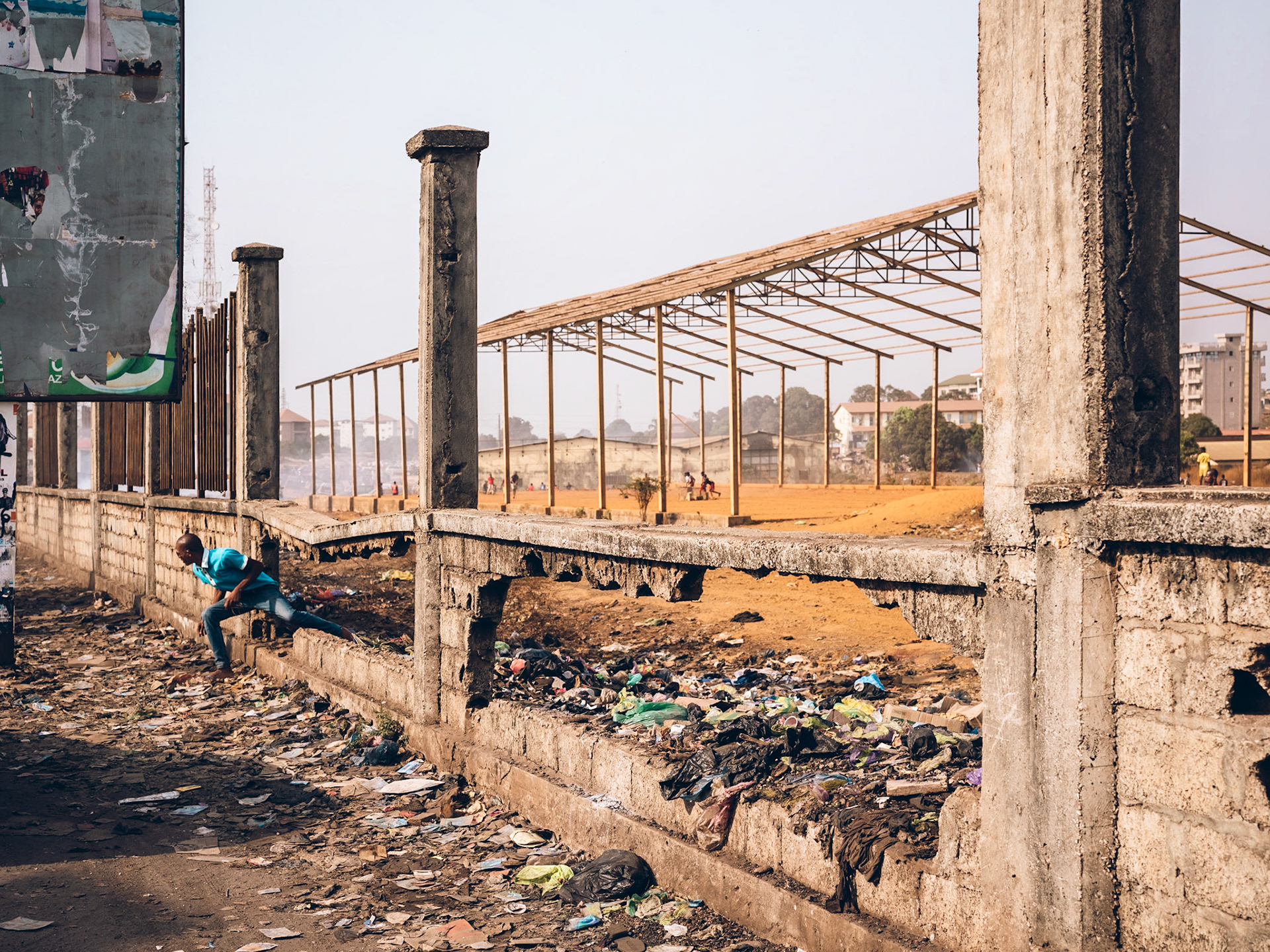A broken wall separates a field from the road in Cosa. Conakry, Guinea.