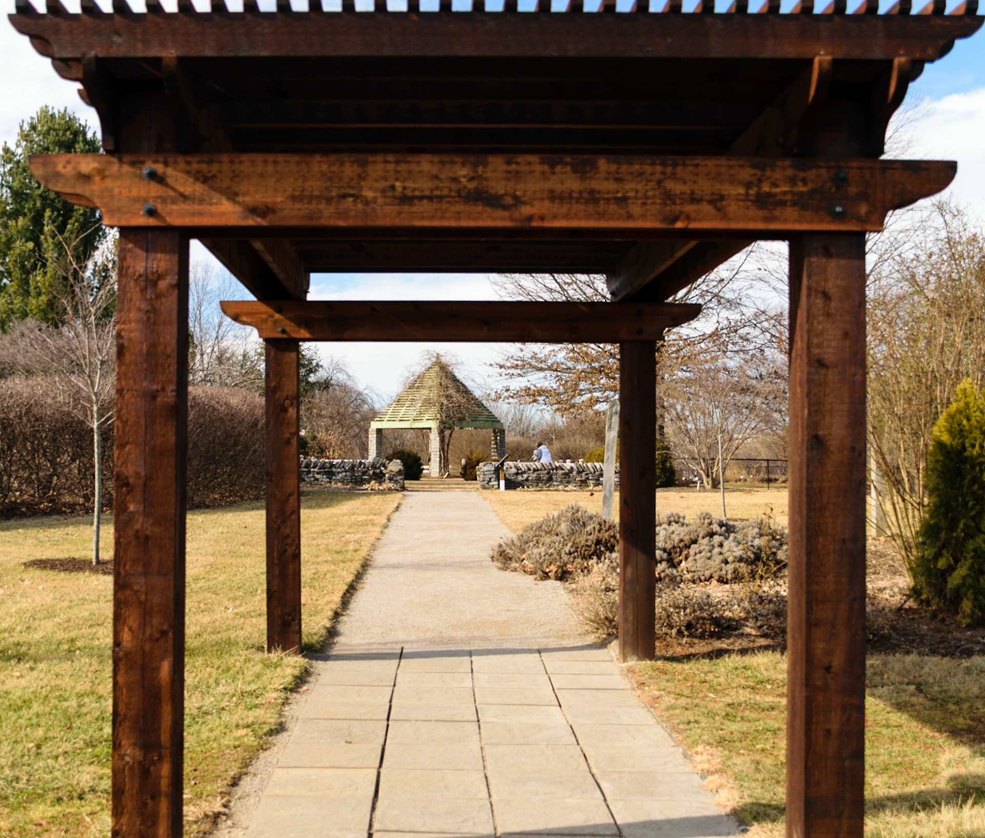 A path runs through an arbor towards a gazebo.