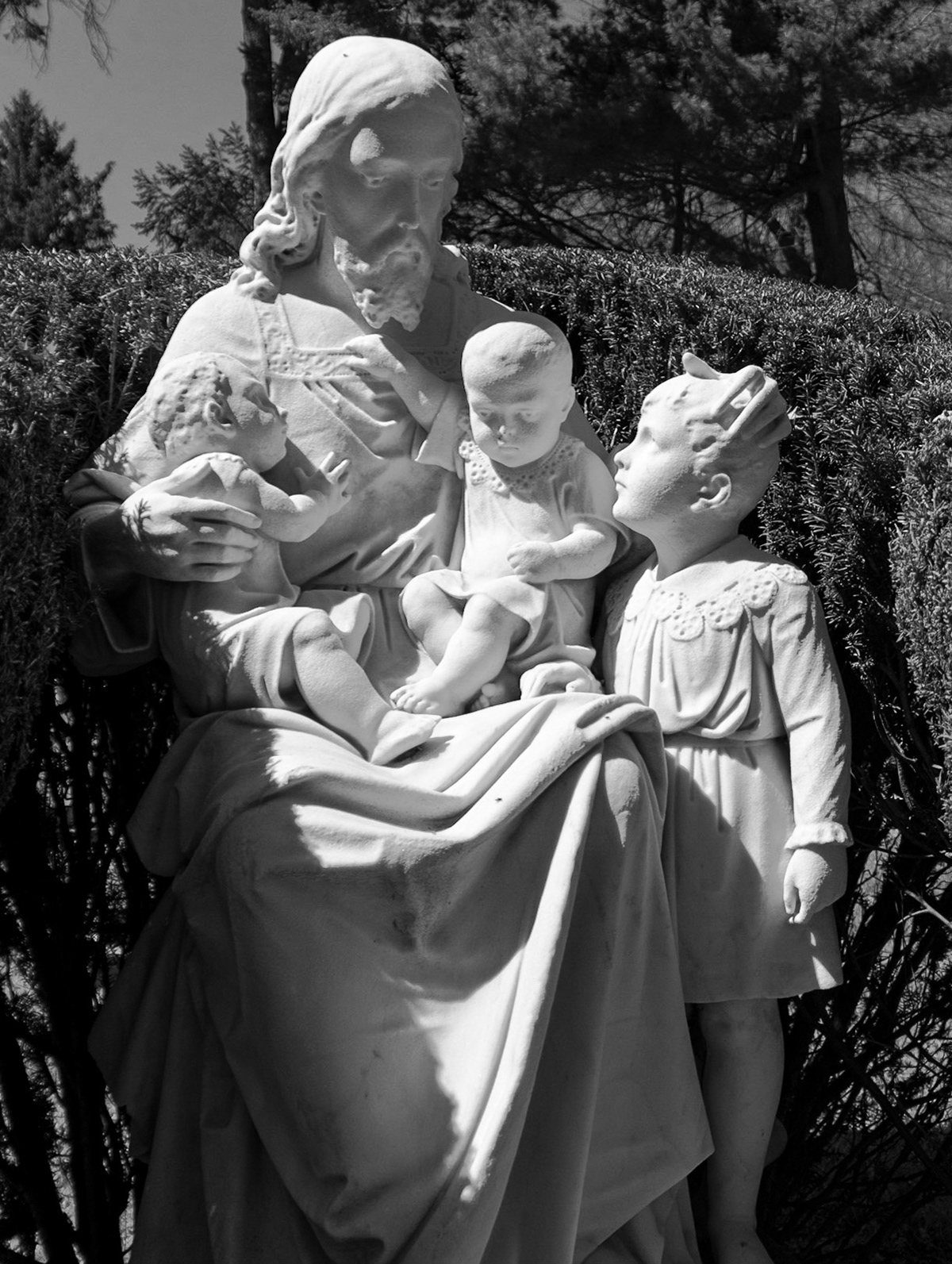 A statue of Jesus holding children is placed in Lexington Cemetary.