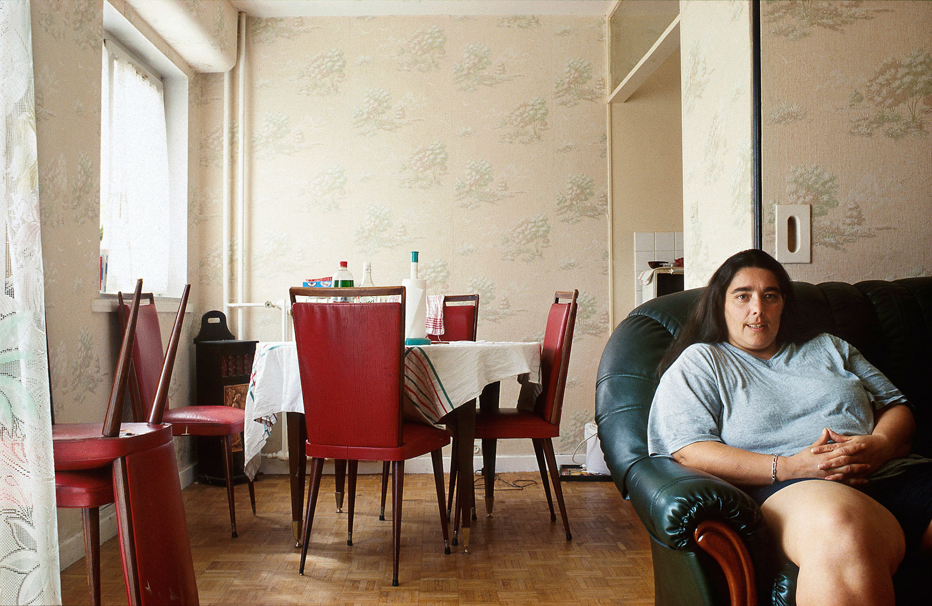 Sandrine a toujours vécu à la Grande Borne. Ses parents sont arrivés en 1969, la cité n’était pas achevée, il y avait encore des champs de betterave et on circulait entre les bâtiments sur des planches de bois. Aujourd'hui, Sandrine travaille à la maison de quartier. Assise à côté d’une statue dorée qui soutient le poste de télévision, elle déplore les problèmes d’isolation et quand le voisin du dessus fait trop de bruit en bricolant, elle tape sur les radiateurs. Si Sandrine s’estime heureuse de la Grande Borne, elle remarque que l’ambiance se dégrade : « Avant on sortait en laissant les portes ouvertes, je ne le ferais plus maintenant. D’ailleurs pas mal de gens partent vers d’autres cités ou pour construire...»