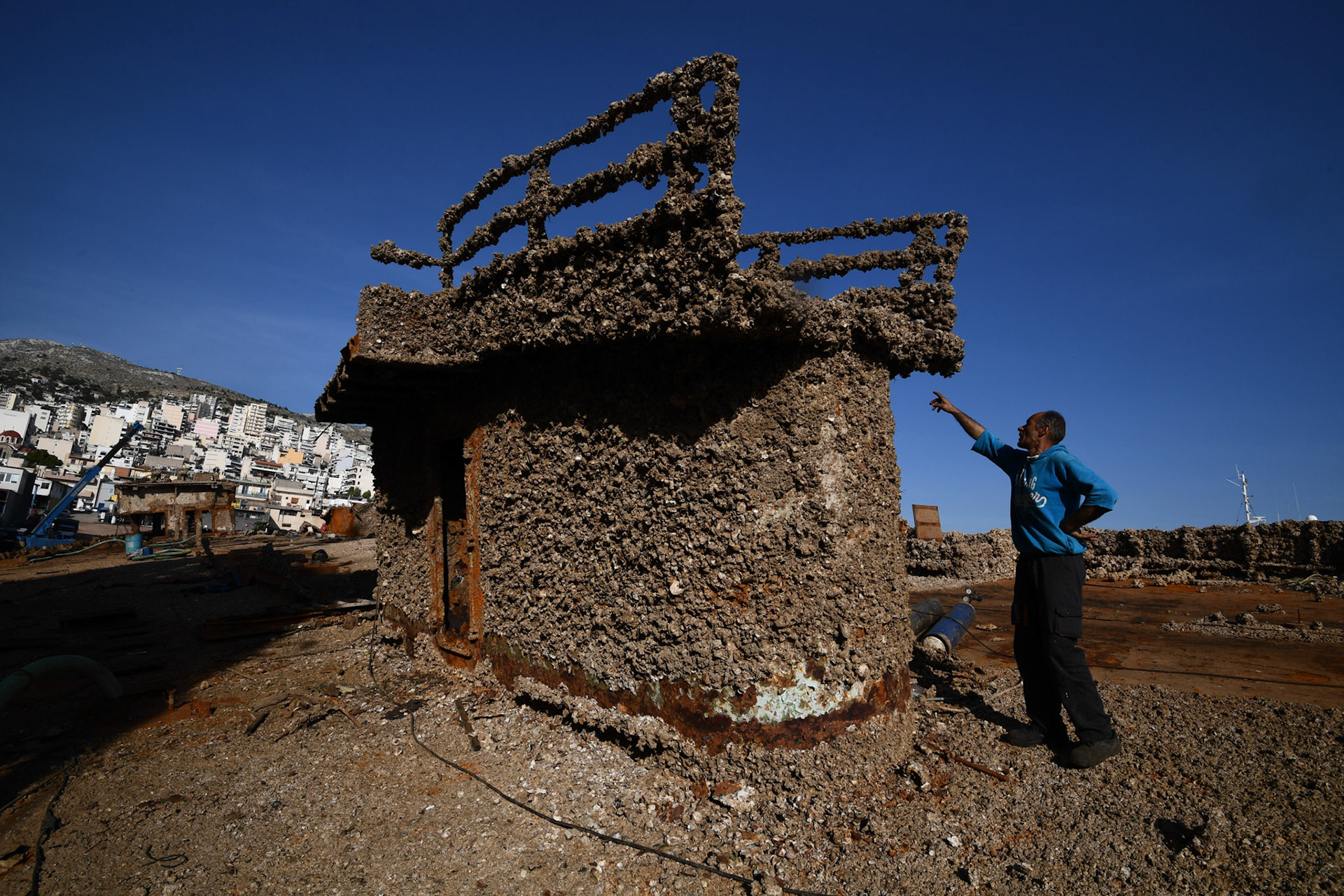 A shipyard worker points part of the “Corfu Island” shipwreck, in the town Perama, west of Athens, Greece, Friday, Nov. 2, 2018.