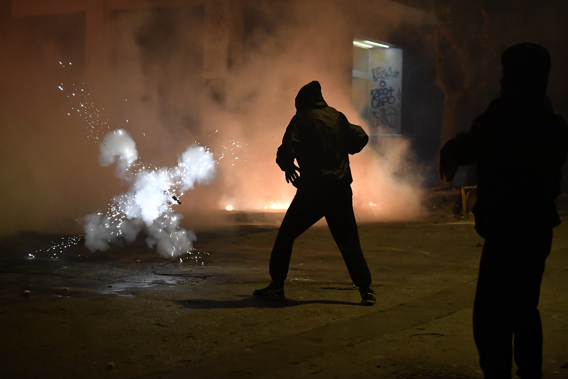 A flashbang explodes infront of a hooded protester, in Exarcheia, Athens, Greece, Thursday, Dec. 6, 2018. Clashes erupted between police forces and protesters during the 10th anniversary of 15 y.o. Alexis Grigoropoulos.