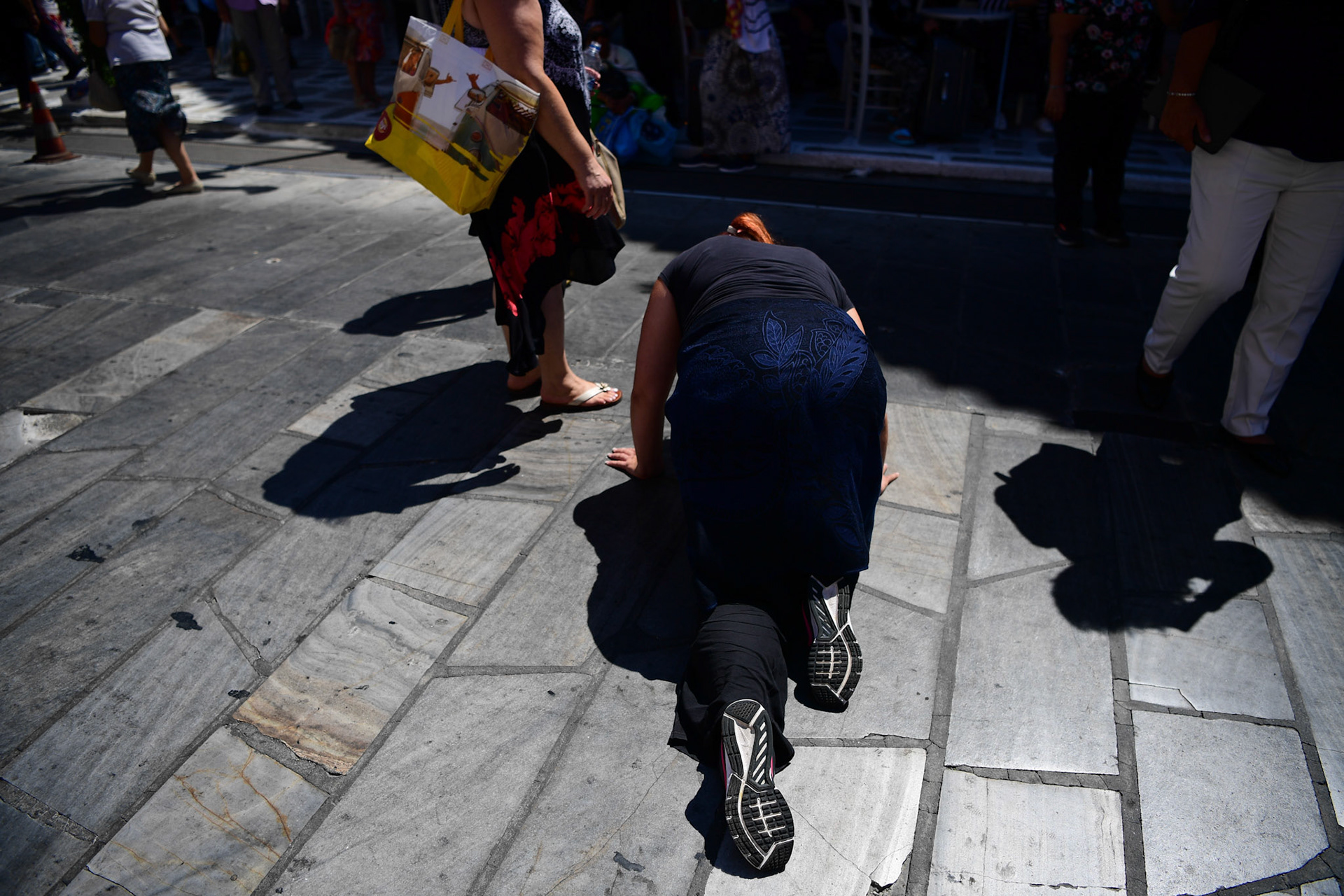 A pilgrim crawls her way to the Greek Orthodox Church of Panagia Evaggelistria amongst other people during the Ascension of Virgin Mary holiday, in Tinos, Greece, Wednesday, Aug. 15, 2018.