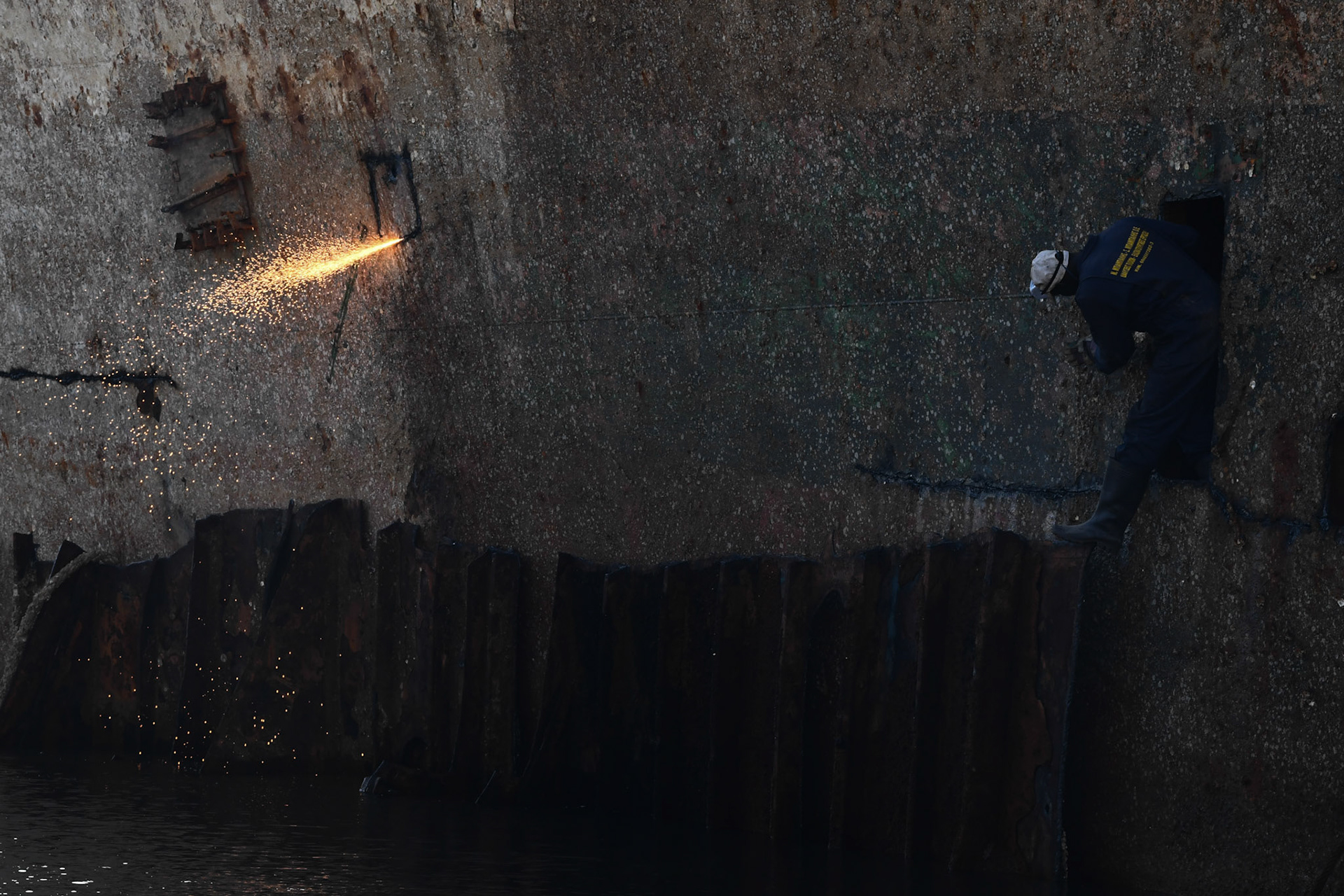 A shipyard worker exits the hull of the “Corfu Island” shipwreck, in the town Perama, west of Athens, Greece, Friday, Nov. 2, 2018.