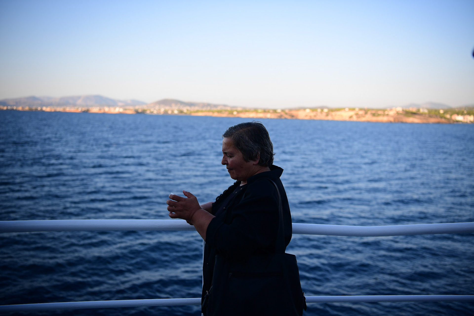 A pilgrim checks her phone on the ferry to the Greek island of Tinos during the Ascension of Virgin Mary holiday, Greece, Wednesday, Aug. 15, 2018.