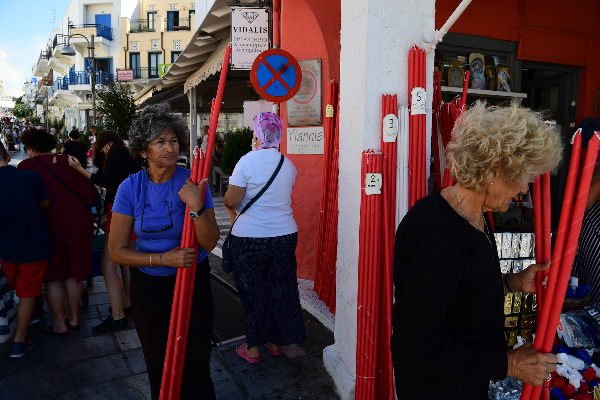 Local shop owners sell candles during the Ascension of Virgin Mary holiday, in Tinos, Greece, Wednesday, Aug. 15, 2018.