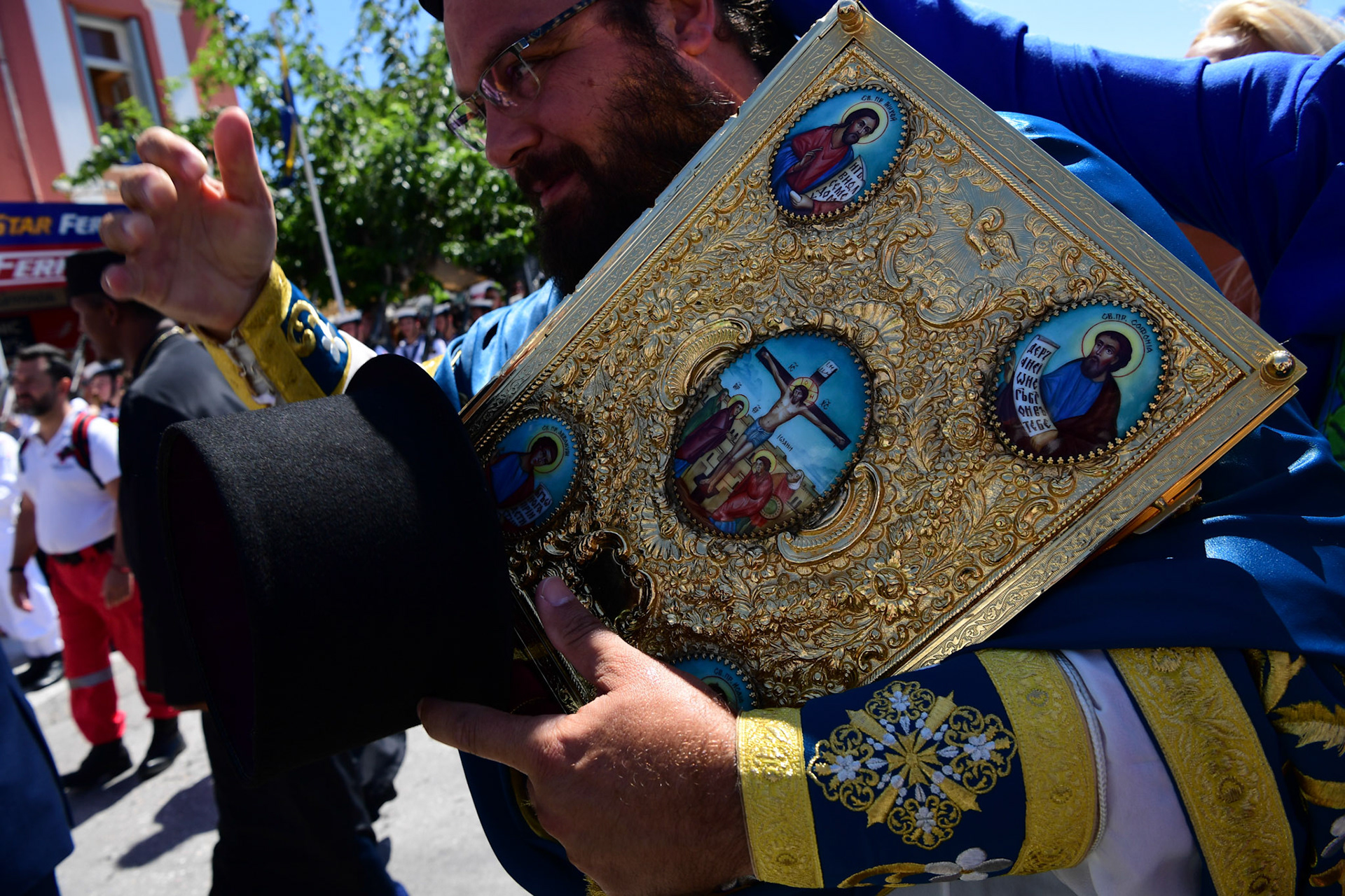 A Greek Orthodox priest holds the Gospel during the Ascension of Virgin Mary holiday, in Tinos, Greece, Wednesday, Aug. 15, 2018.