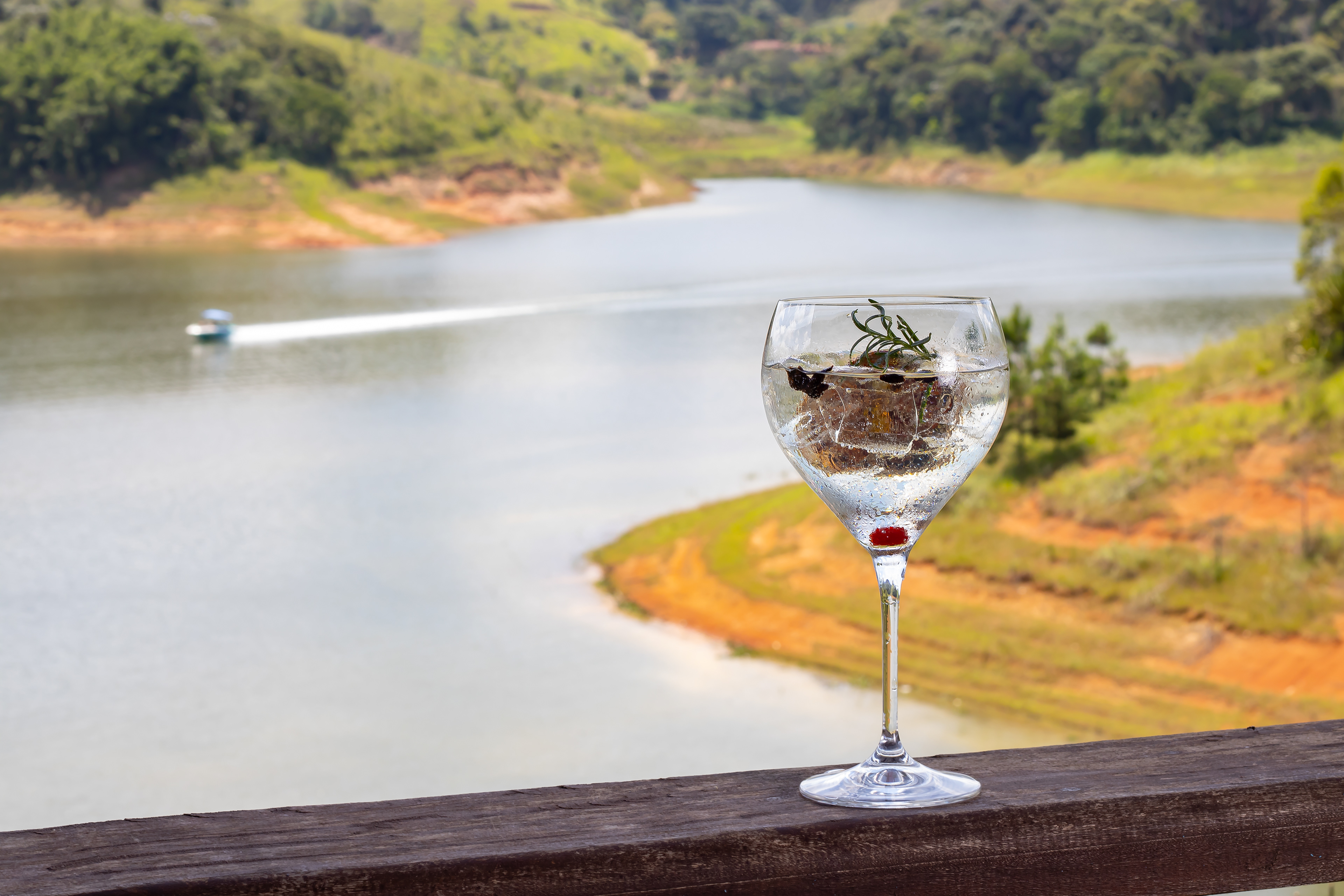 Fotografia de gin com fundo de lago com barco passando,  Recanto Apoena