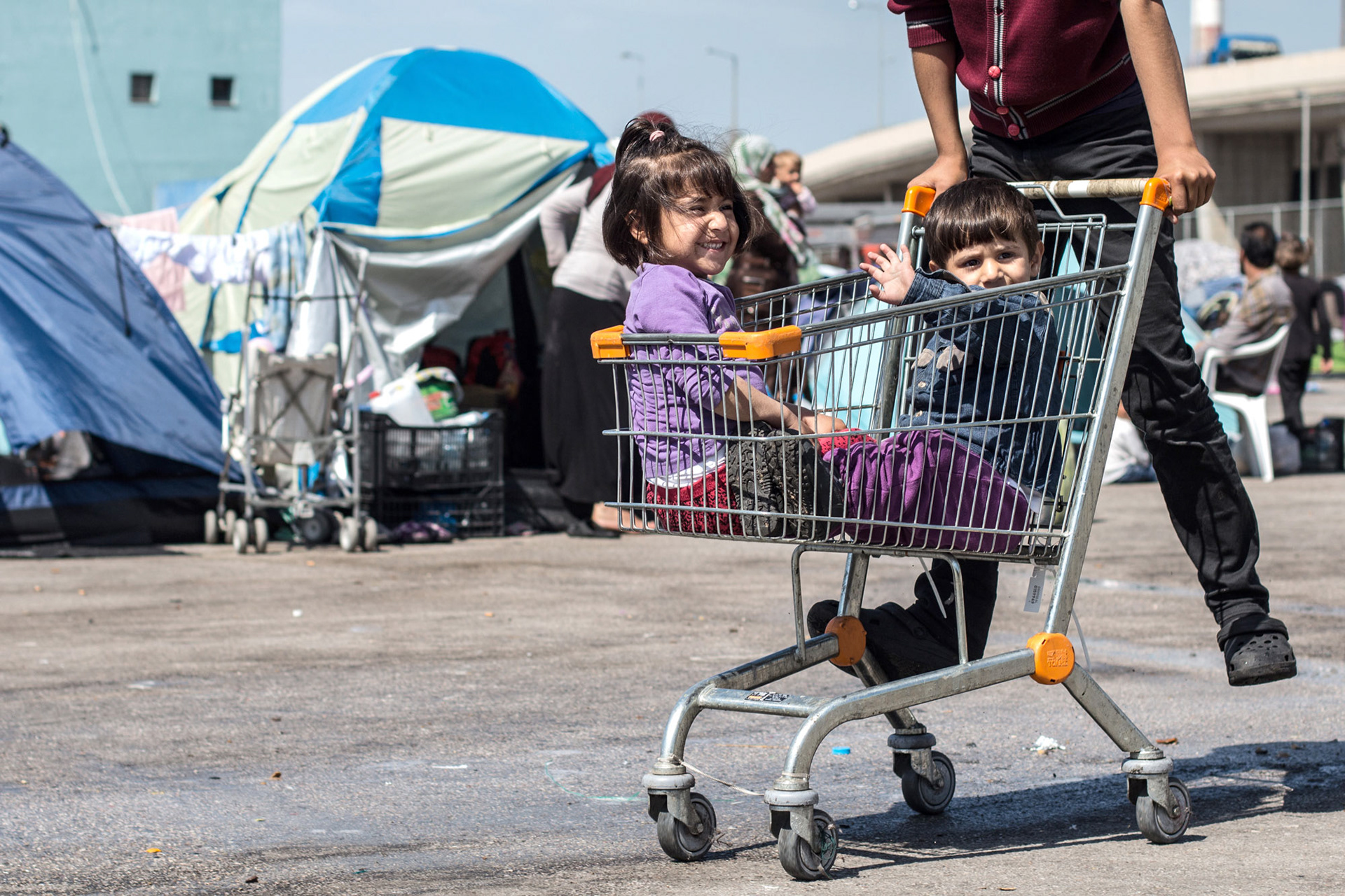 Refugee children playing with shopping cart - Piraeus, Greece © Fotis Providas