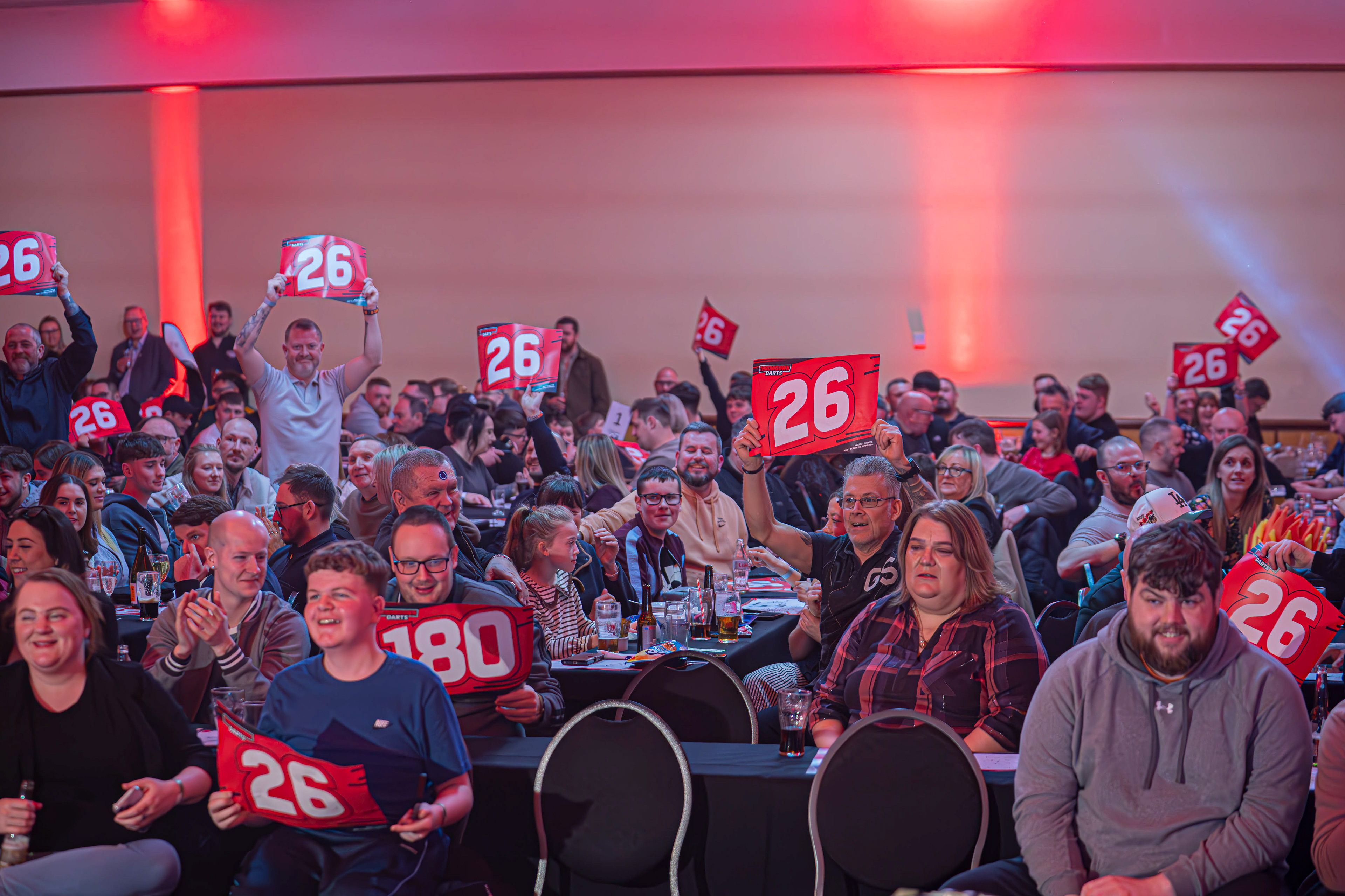 Fans holding up a 26 scorecard in the crowd as Heyzy Darts hits a score of 26 at the Copthorne Hotel, Brierley Hill. 27/03/26