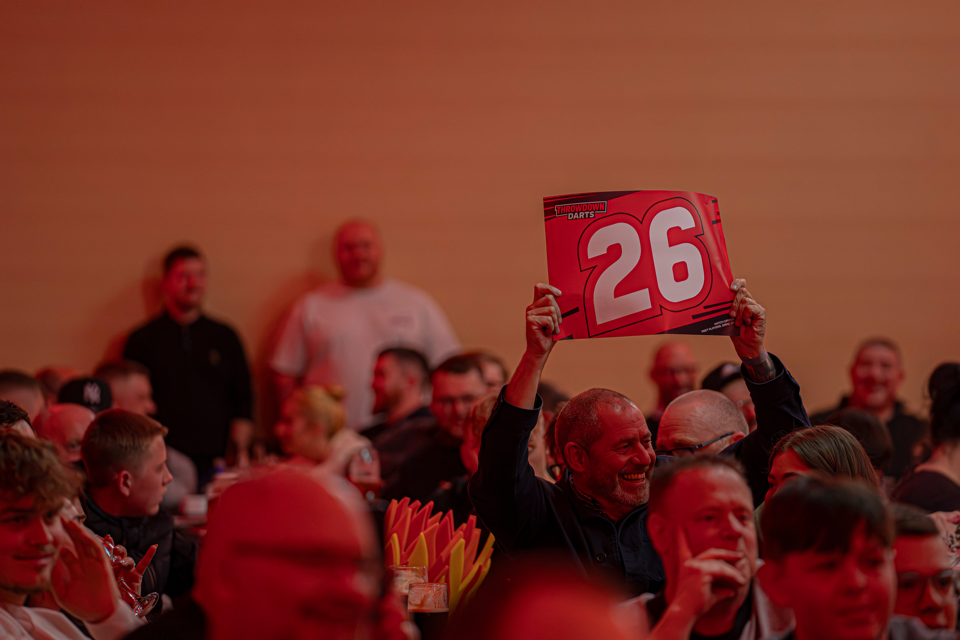 Fan holding up a 26 scorecard in the crowd as Heyzy Darts hits a score of 26 at the Copthorne Hotel, Brierley Hill. 27/03/26