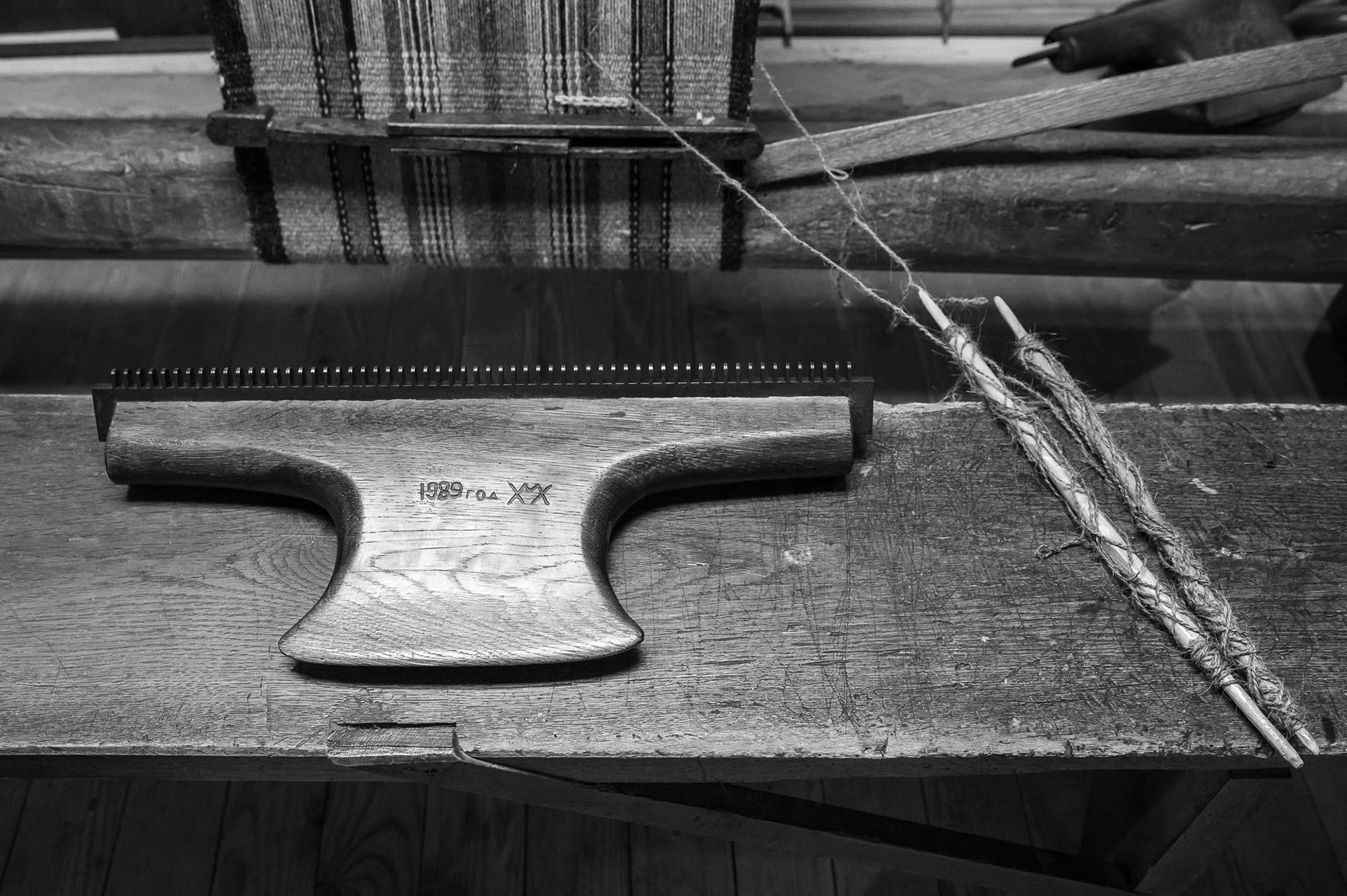 The tarak tool (a heavy comb with metal tines and a wooden handle) is used to beat the threads when weaving the cloth