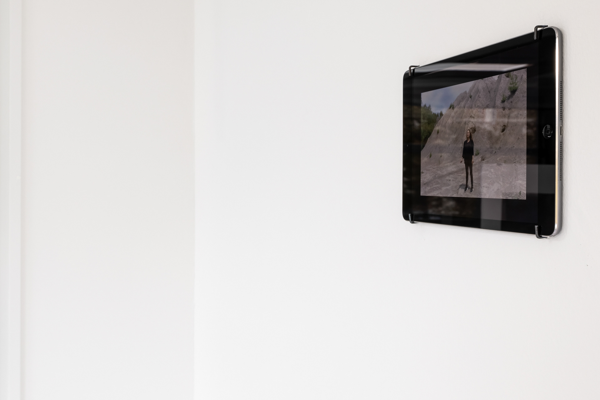 Installationsansicht: iPad, Künstlerin in Außendienstkleidung in Landschaft