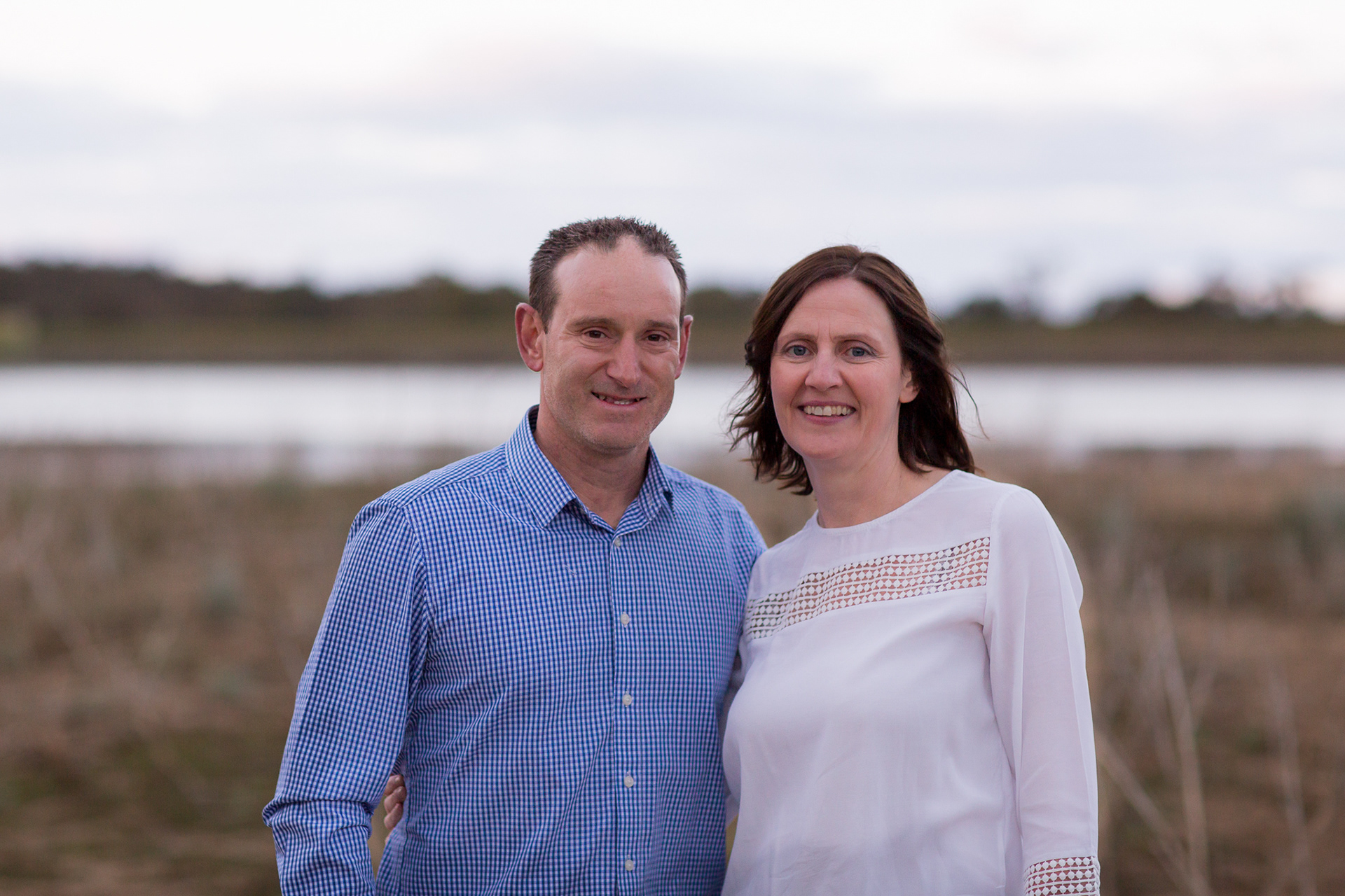 husband and wife together smiling wiht water landscape in the background