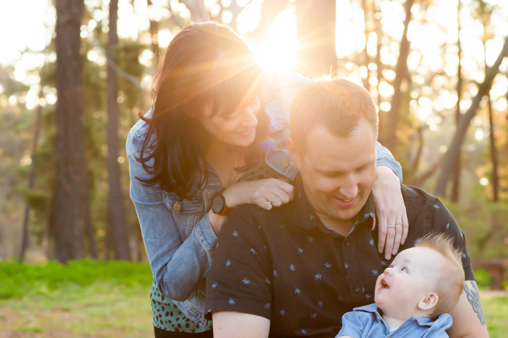 Mother, father and baby with sun flare in the back ground