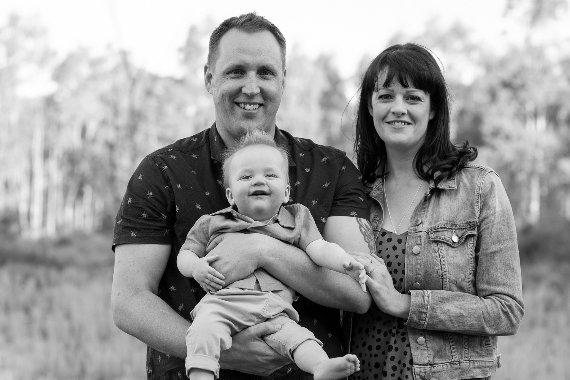 Mother, father and baby portrait all smiling. Black and white image