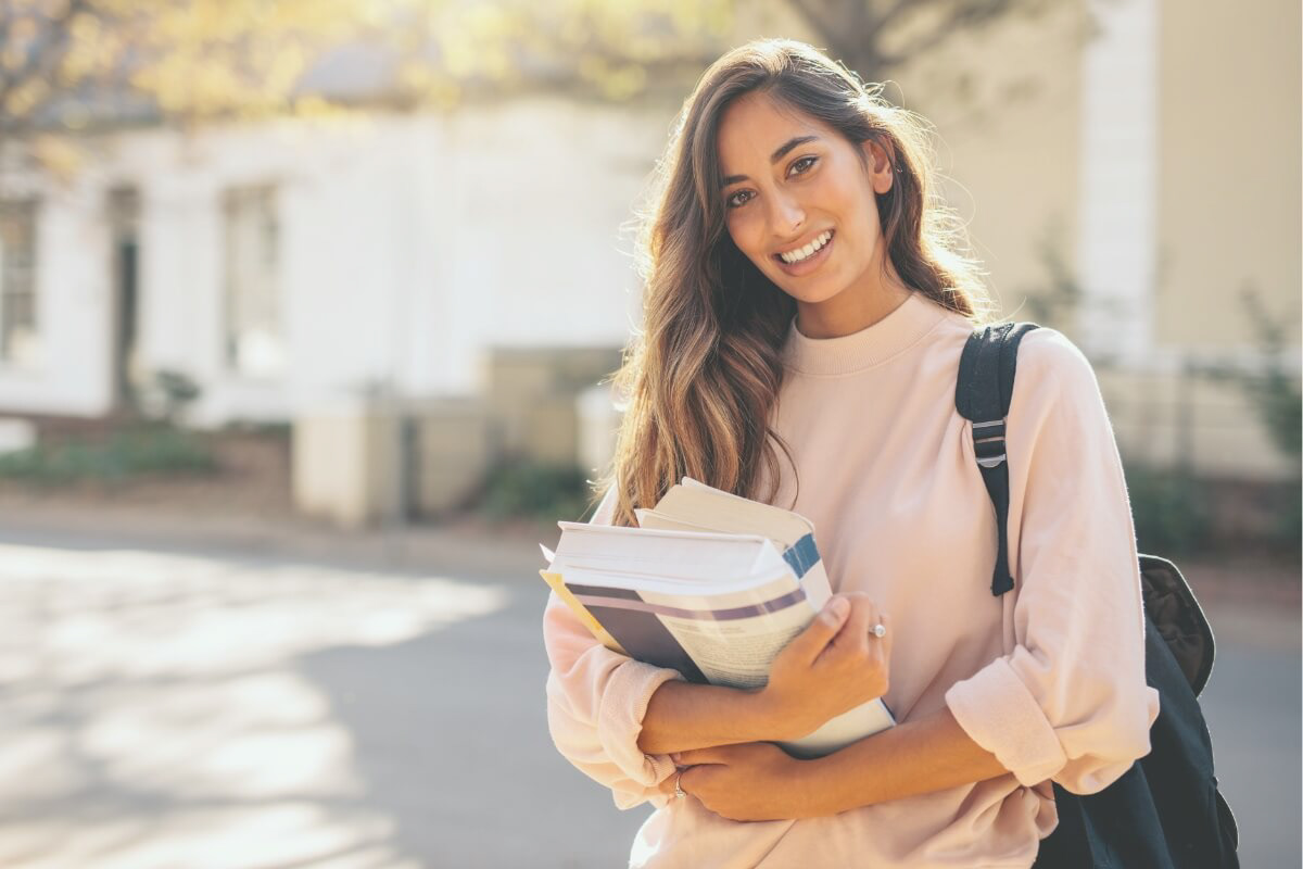 Photo of a university student holding books in her arms