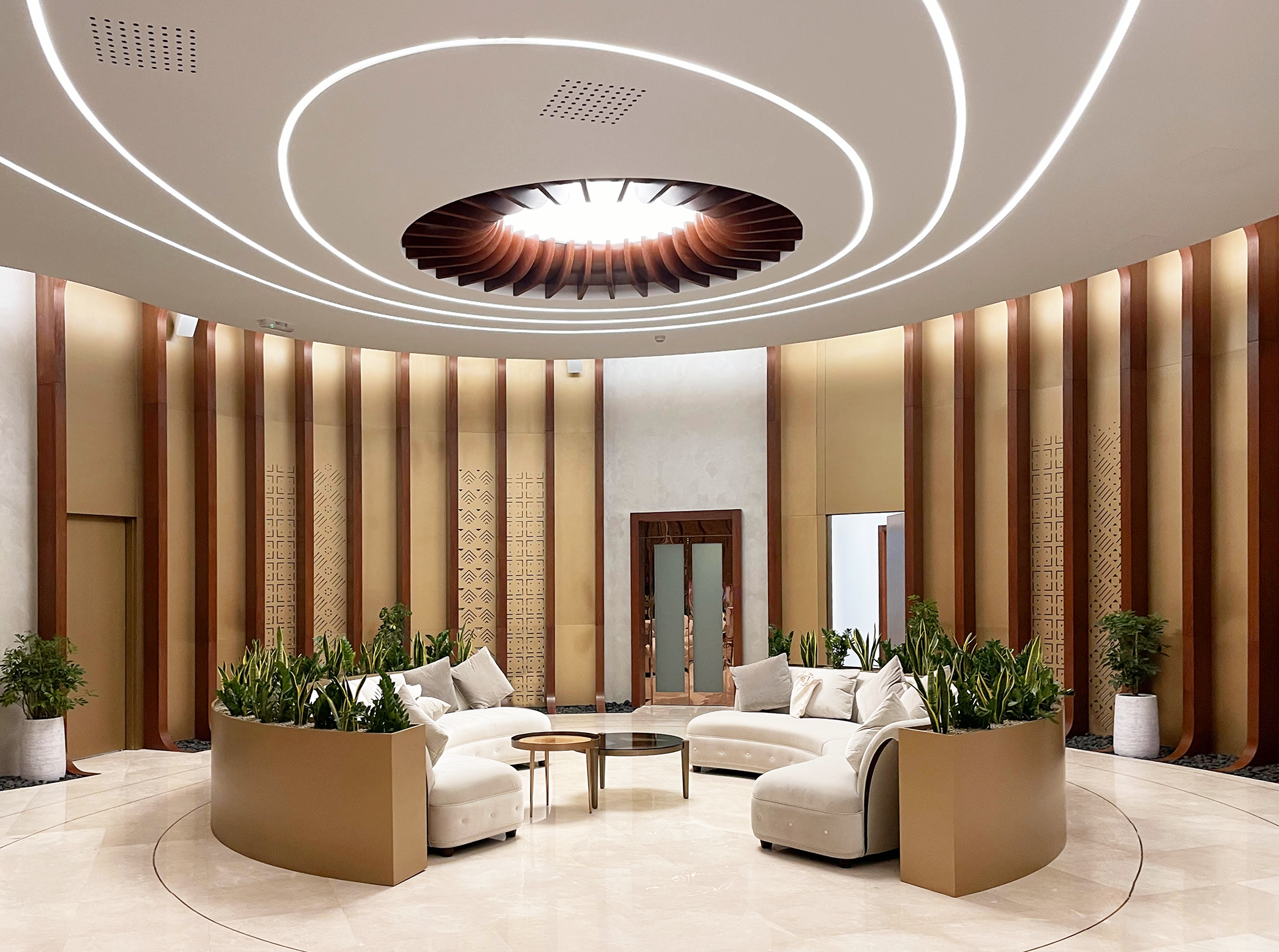 Majlis room with a circular white sofa, warm gold panels, and plants