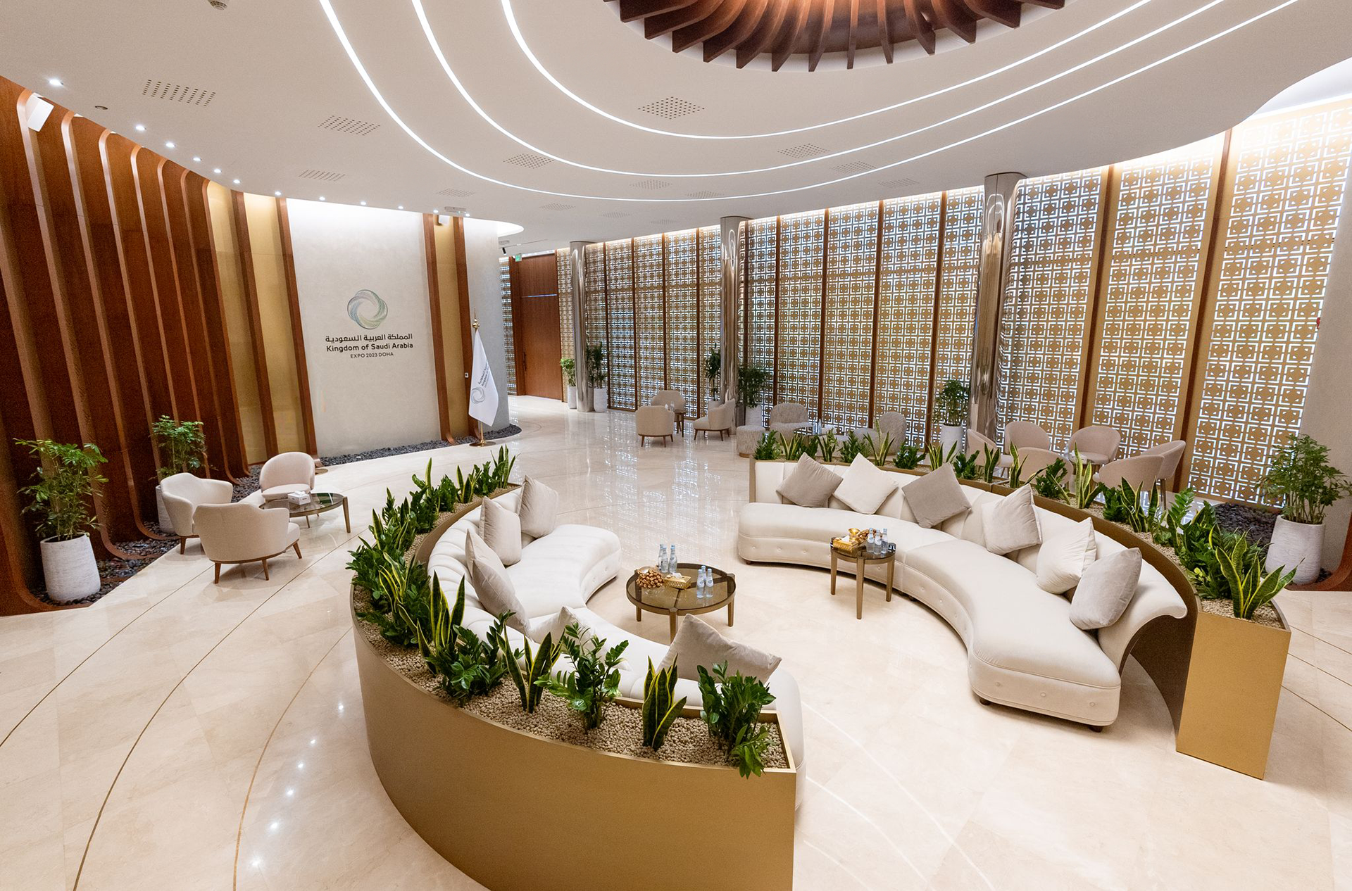 The white circular sofa in the middle of the majlis room, adorned with decorative plants